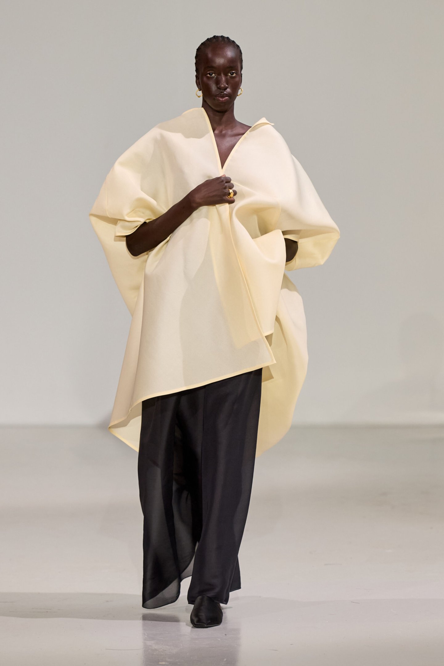 Modelo desfila em Copenhagen Fashion Week de 2026 com traje bege volumoso e calças pretas.