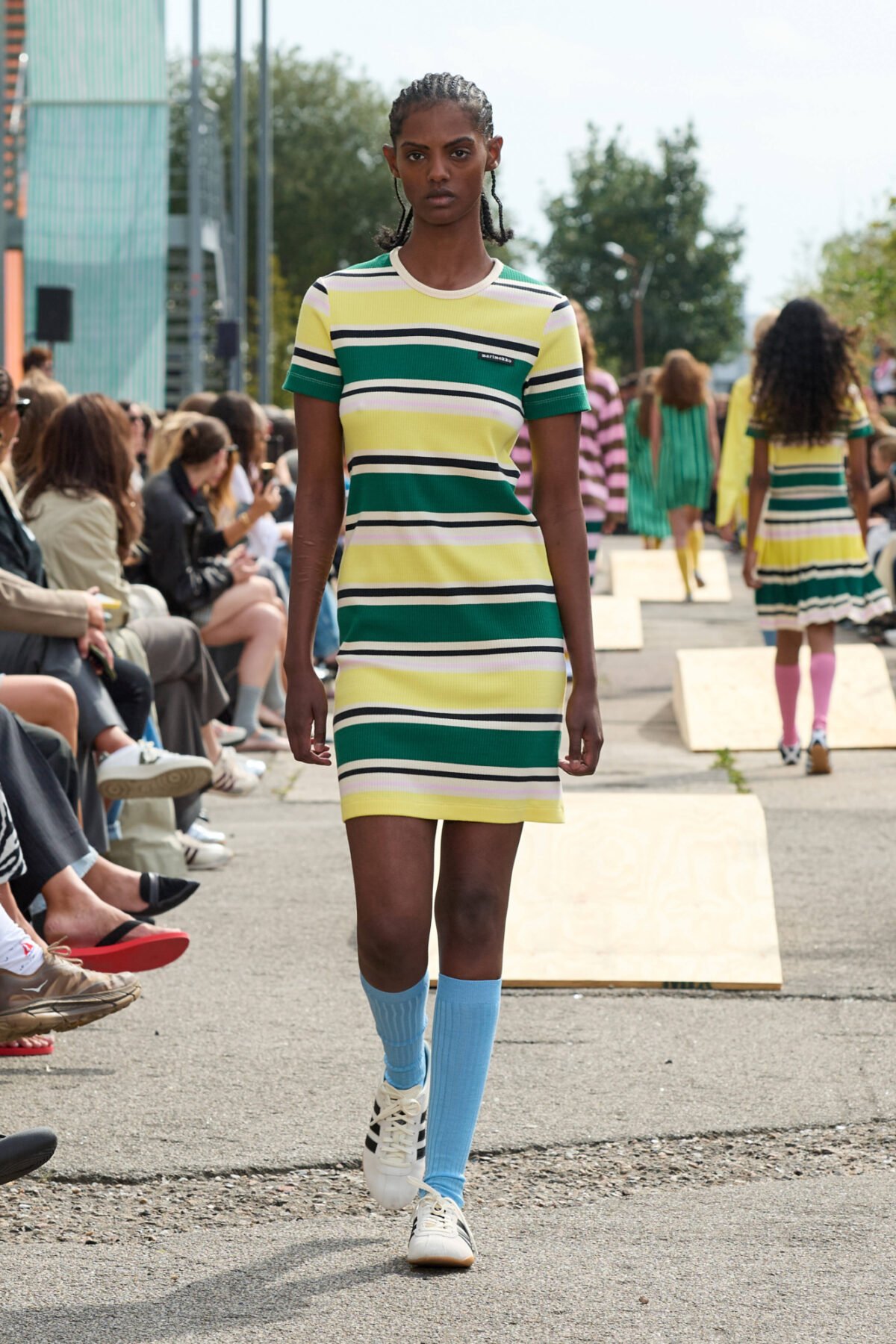 Desfile da Copenhagen Fashion Week Spring 2026, modelo em vestido listrado colorido e meias azuis.