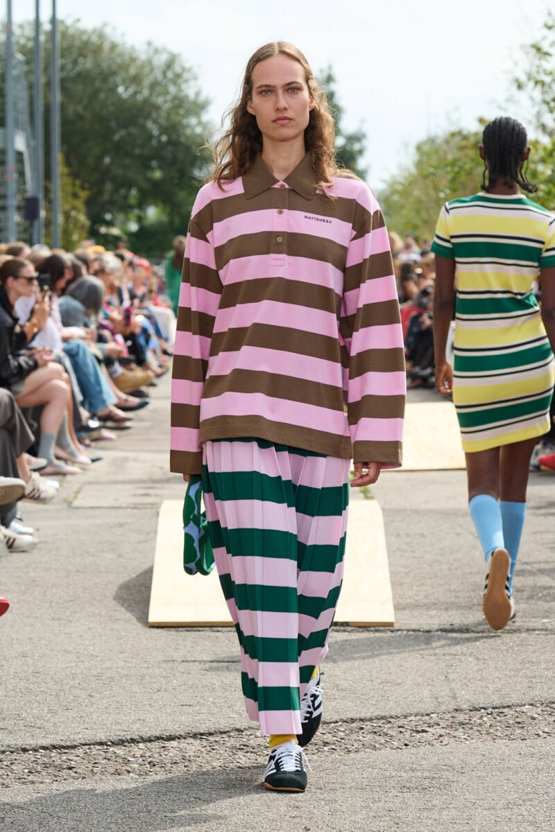 Desfile ao ar livre com modelo usando roupas listradas nas cores rosa, marrom e verde. Copenhagen Fashion Week Spring 2026.