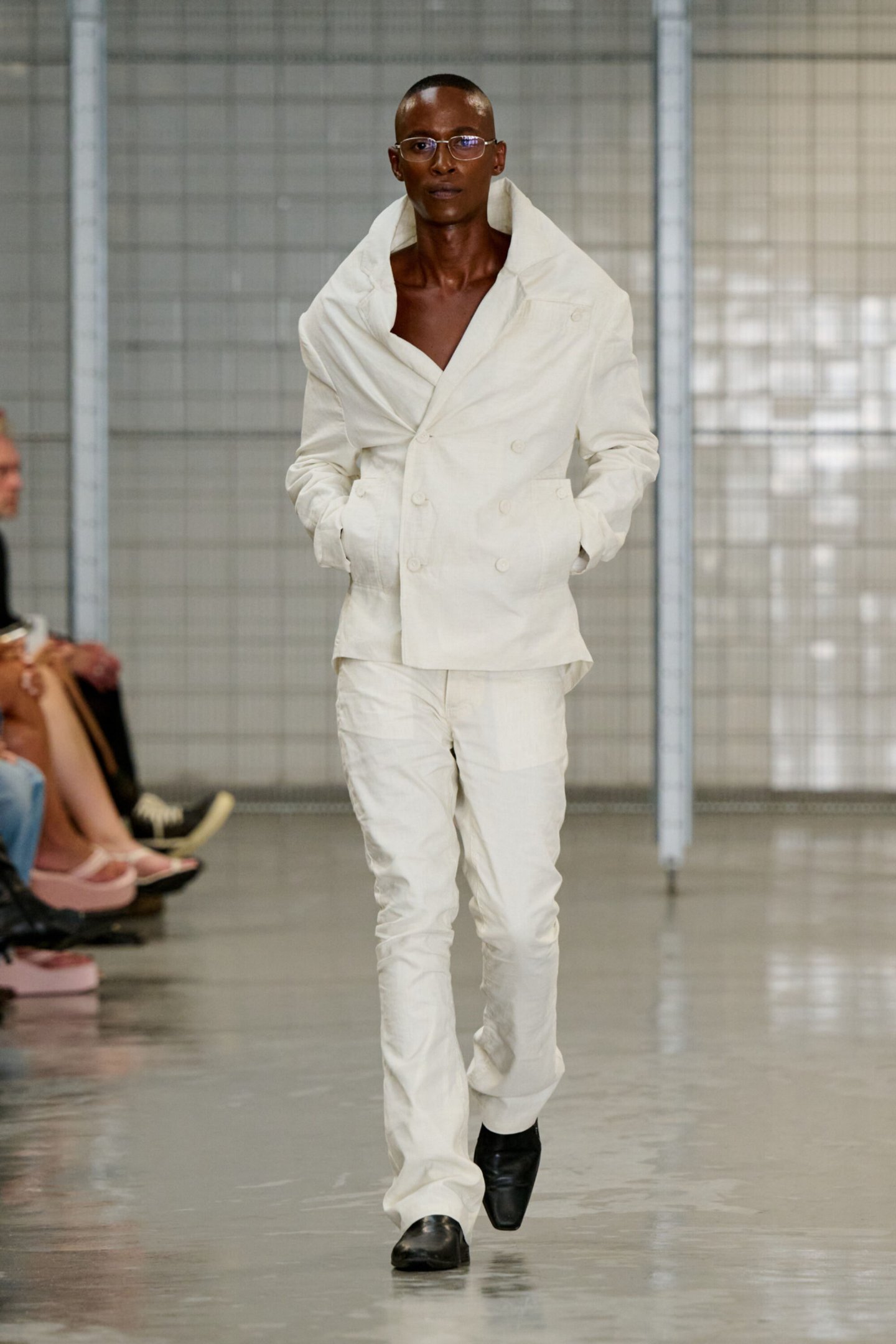 Modelo desfila com terno branco elegante e óculos, na Copenhagen Fashion Week Spring 2026.
