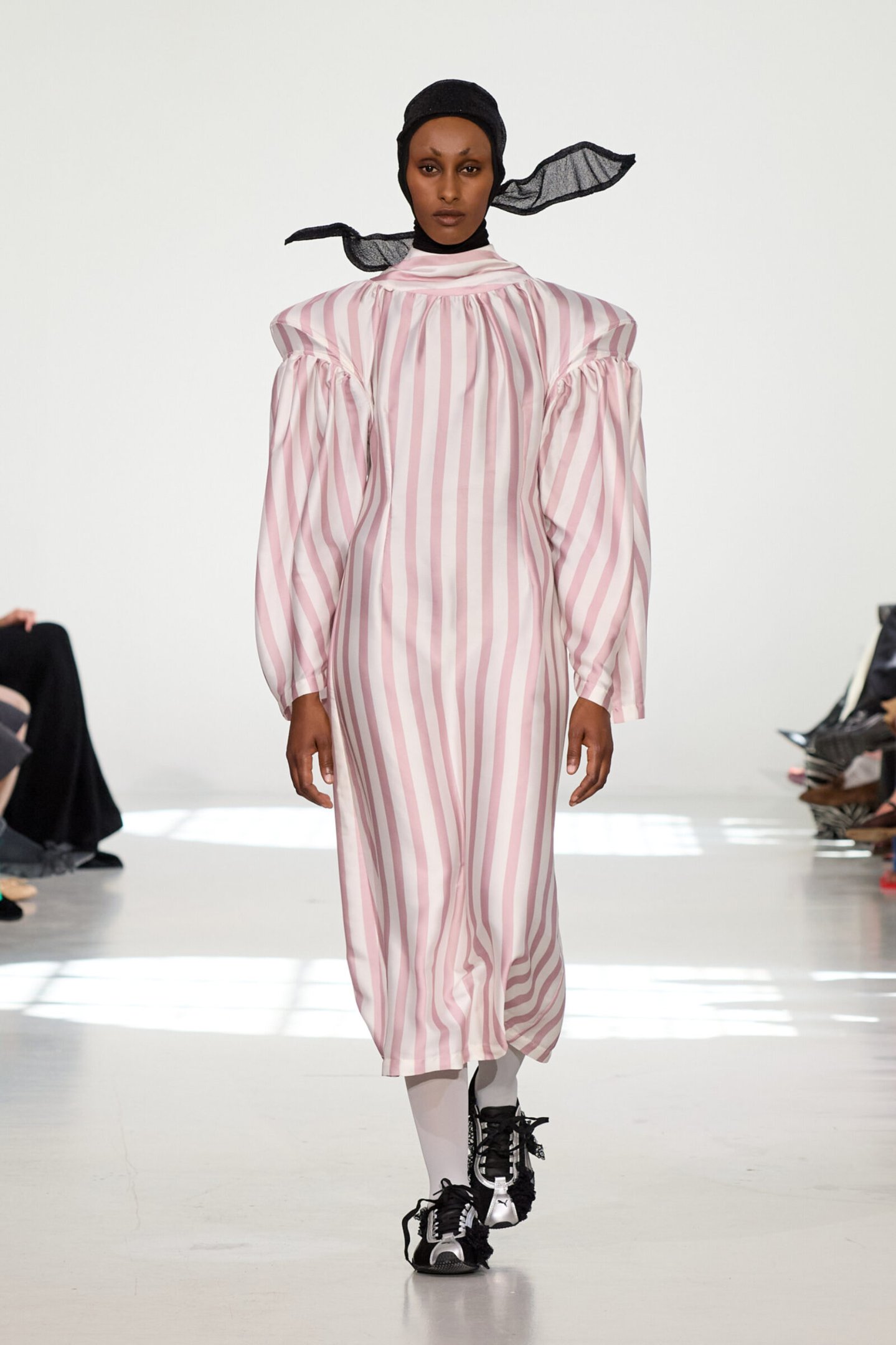 Modelo veste vestido listrado rosa e branco, complementeando com sapatos esportivos pretos. Copenhagen Fashion Week 2026.