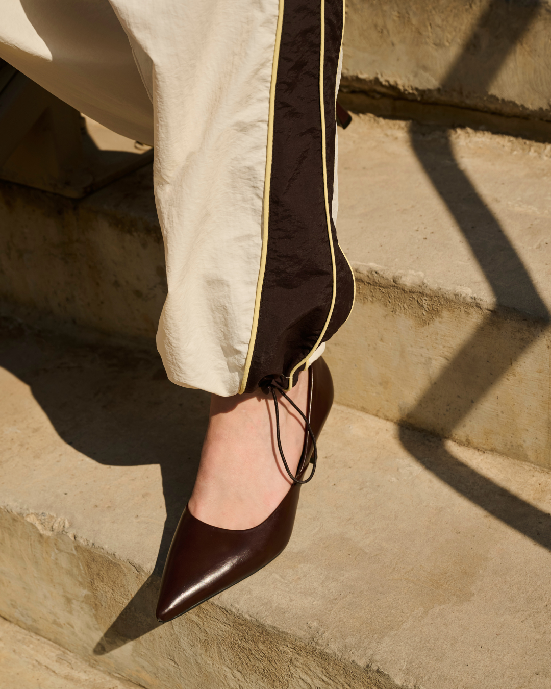 Calça esportiva com salto fino, combinando elegância e conforto em uma escada de cimento sob luz solar. mostrando como ficar chique e confortável com a nova coleção de renner