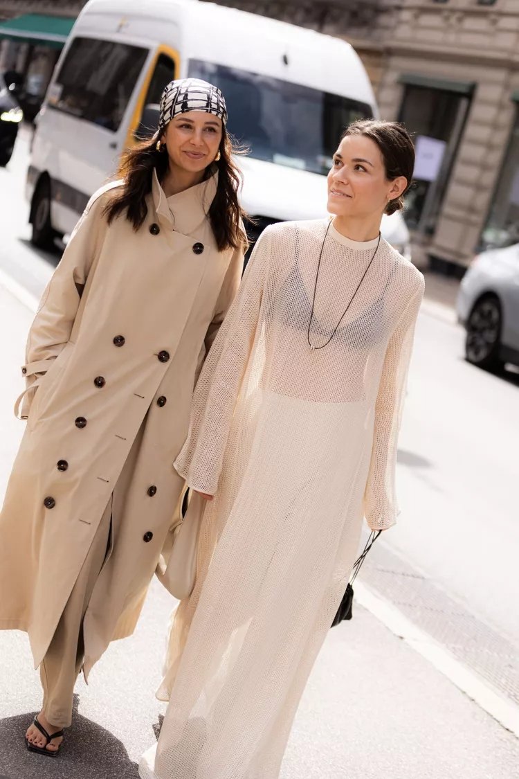 Duas mulheres sorrindo com looks elegantes e neutros, representando o estilo de rua da Copenhagen Fashion Week.