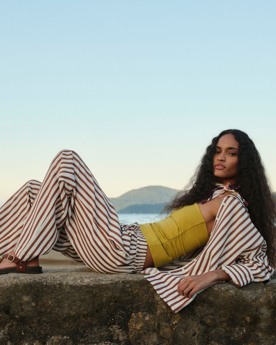 mulher usando conjunto de calça e camisa listrada, com blusa verde, uma das tendências de primavera verão