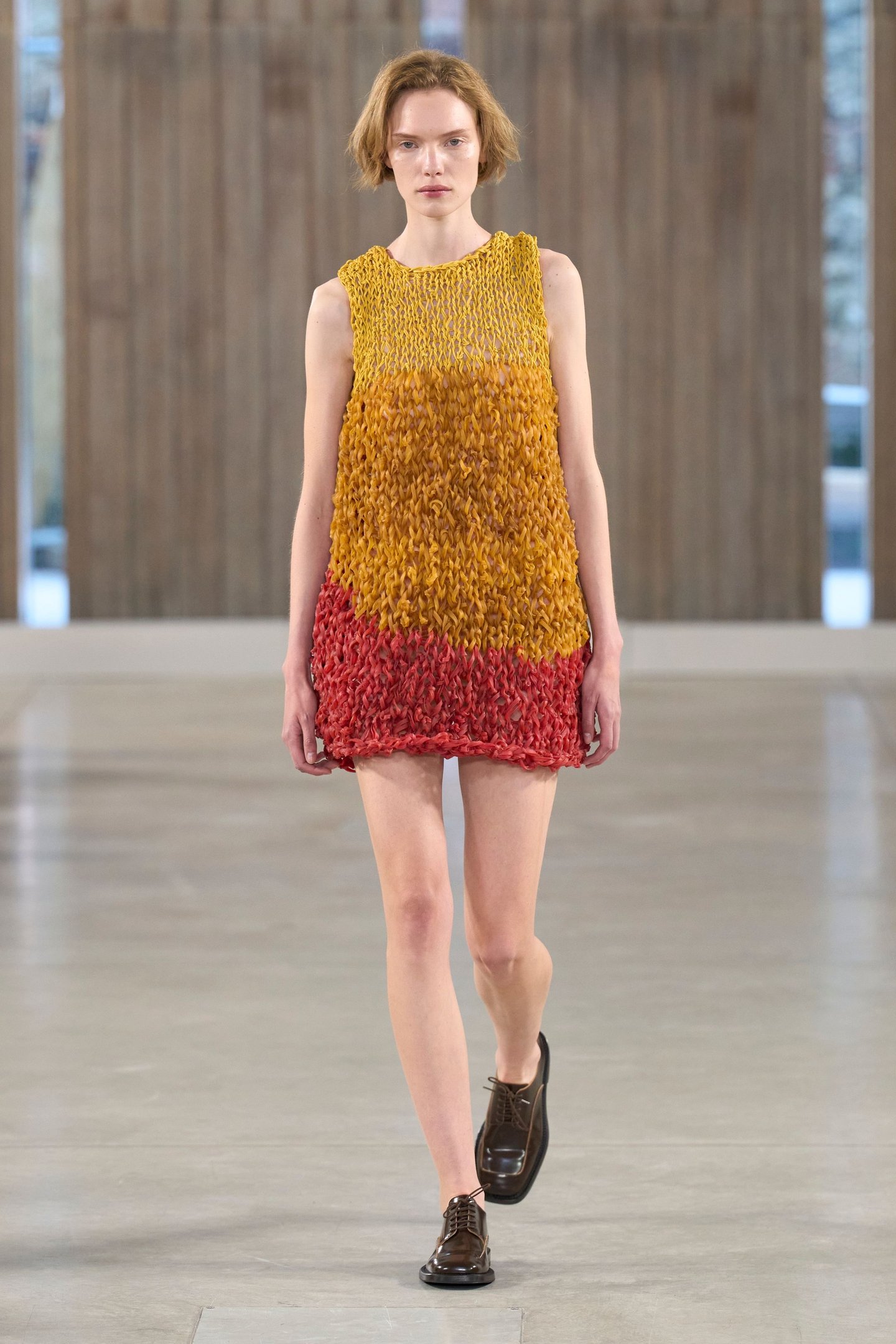 Vestido texturizado nas cores amarelo e vermelho, combinado com sapatos marrons na Milan Fashion Week SS26.