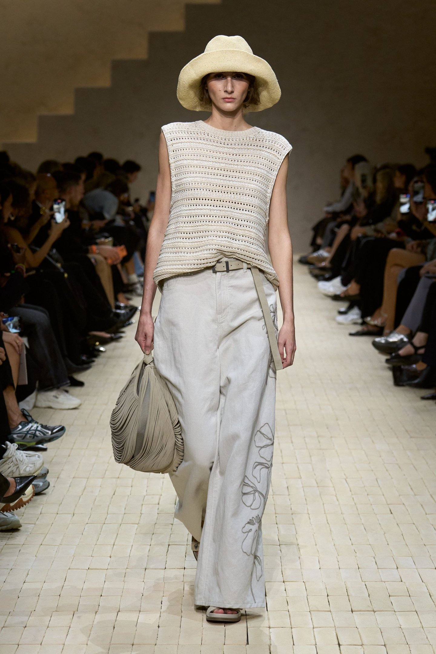 Modelo desfila com chapéu de palha, blusa de crochê e calça bege larga. Evento: Milan Fashion Week SS26.