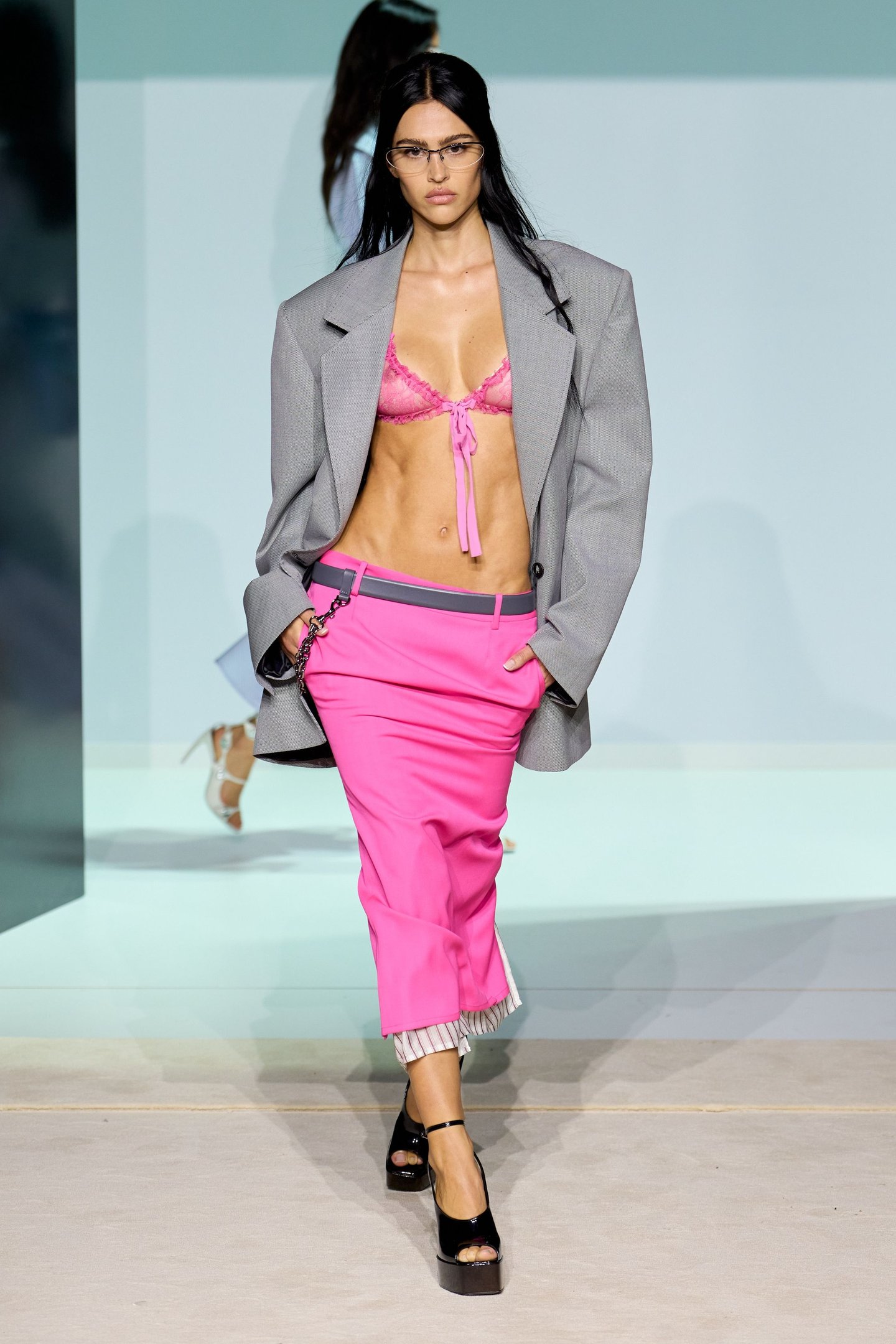 Modelo em passarela com blazer cinza, sutiã rosa e calça pink na Milan Fashion Week SS26.