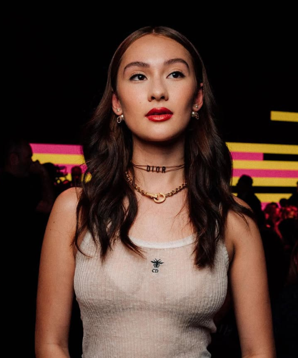 Pessoa com cabelo ondulado forte por causa do melhor shampoo para queda de cabelo e maquiagem destacada em ambiente iluminado por luzes neon.