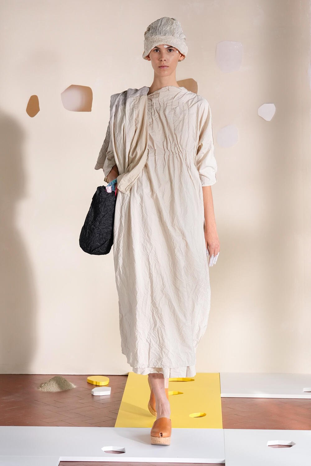Modelo com vestido bege e chapéu combinando na passarela da Milan Fashion Week SS26.