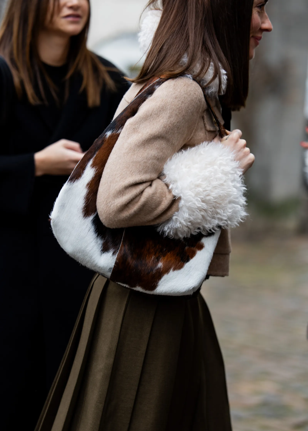 Mulher segurando bolsa com estampa estilosa de pele sintética em tons de marrom e branco.