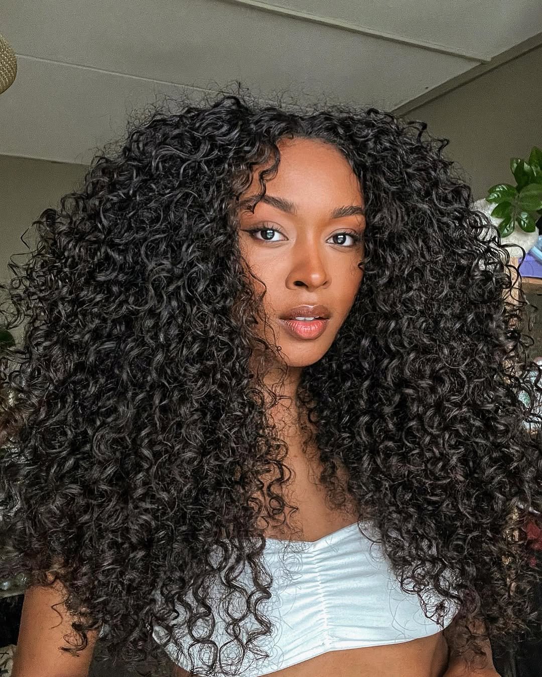 Cabelo cacheado longo volumoso e definido moldando o rosto de uma mulher.