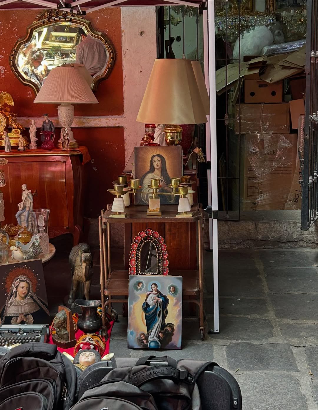 Antiguidades e imagens religiosas exibidas em loja na Cidade do México, incluindo quadros e espelhos.
