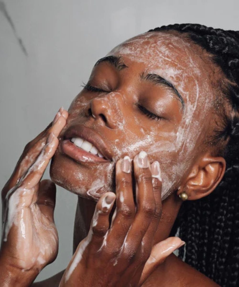 Pessoa aplicando loção facial para limpar a pele, possivelmente como parte de uma rotina para tratar cravos.