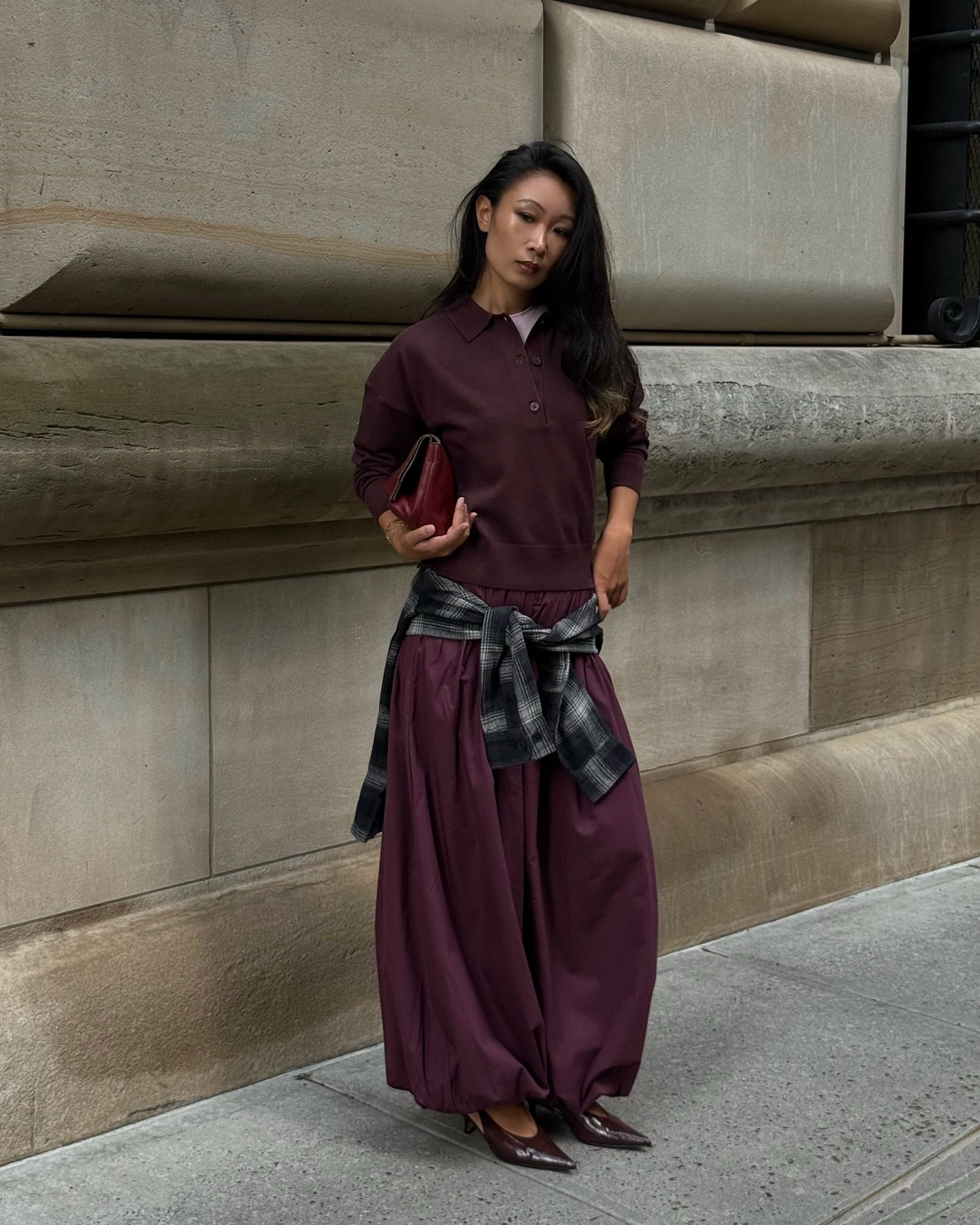 Mulher usando calça aladim vinho e blusa combinando, com camisa xadrez amarrada na cintura.