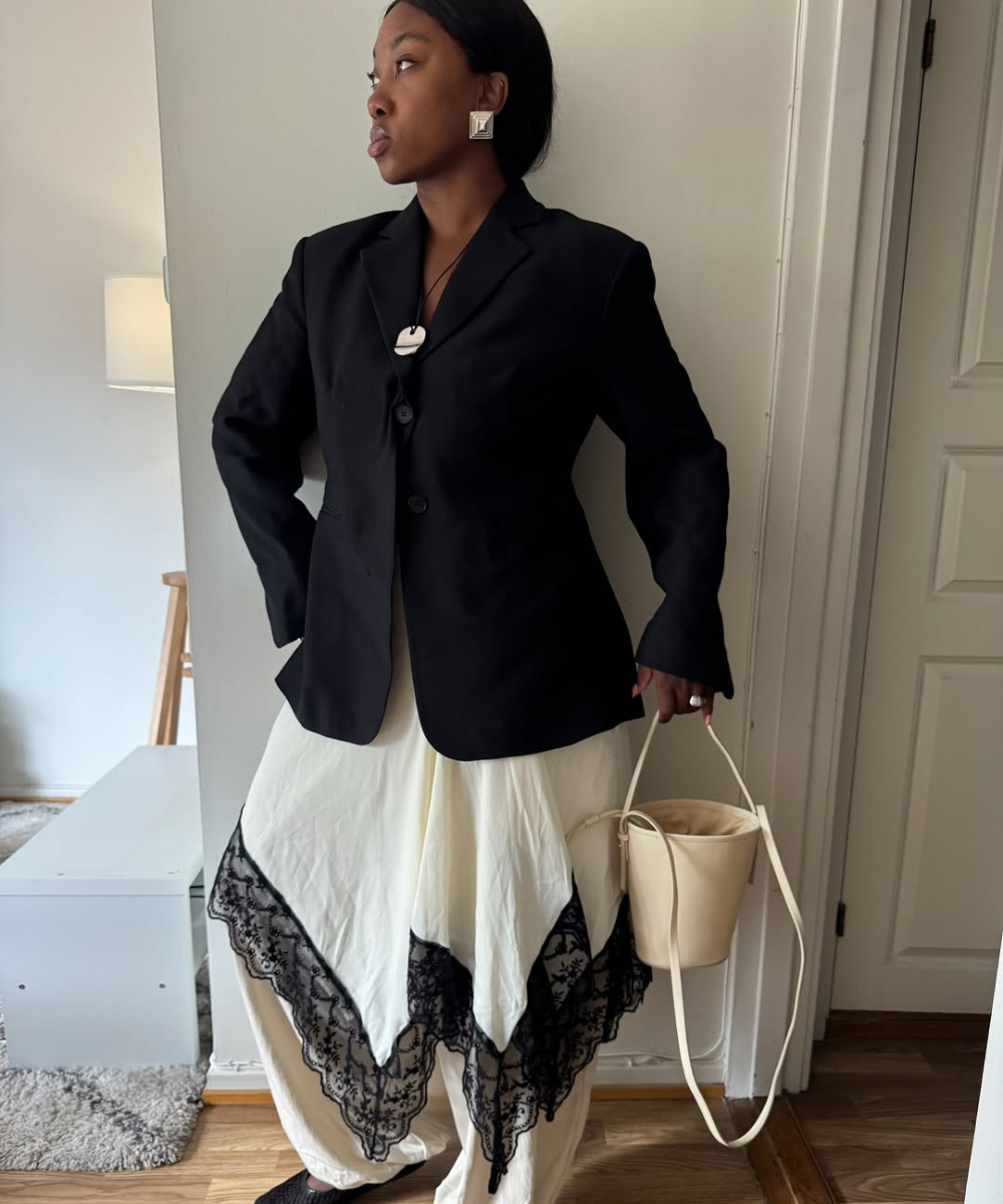 Renda preta destaca a saia sobre calça branca, combinada com blazer preto elegante.