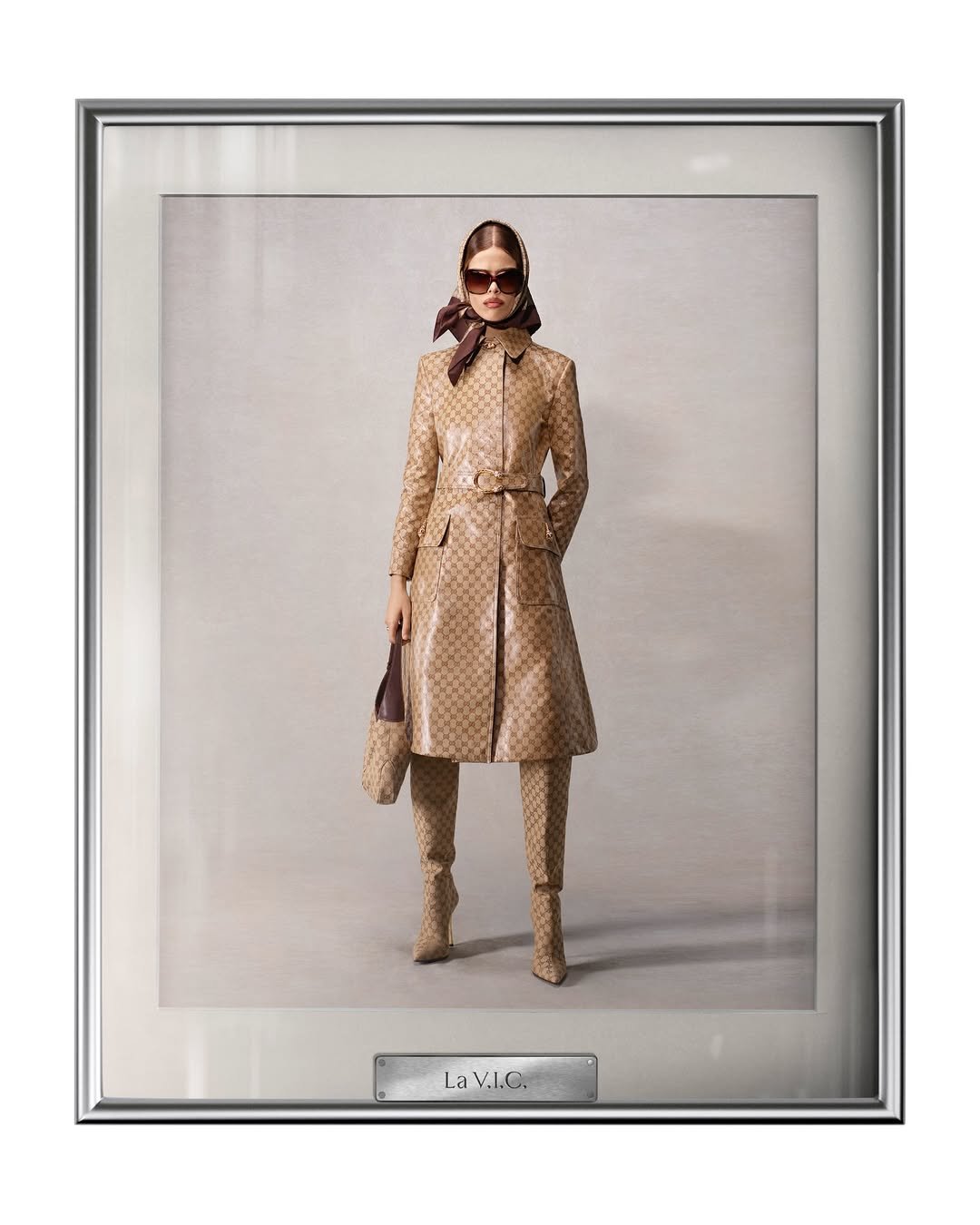 Modelo veste conjunto marrom elegante com padrão repetido, lenço marrom e óculos escuros. Gucci de Demna