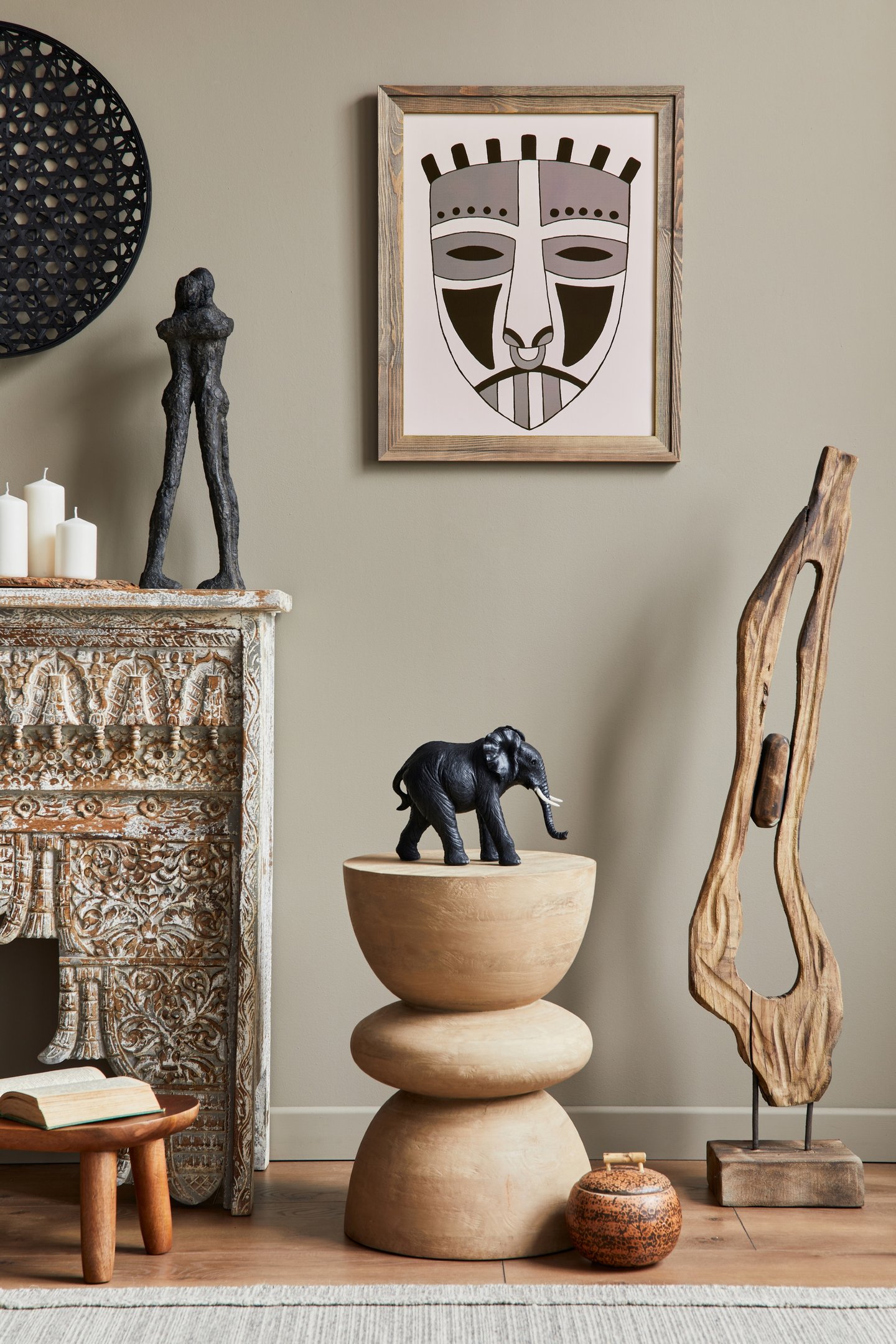 Ambiente decorado com objetos artísticos, incluindo uma escultura, máscara tribal e ornamentos. Dicas de decoração boêmia.