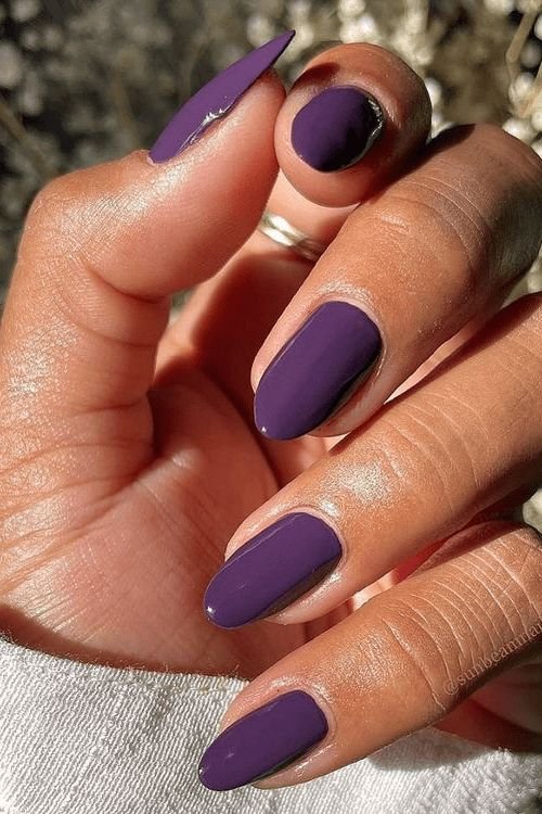 Unhas com esmalte roxo exibidas sob a luz solar intensa.