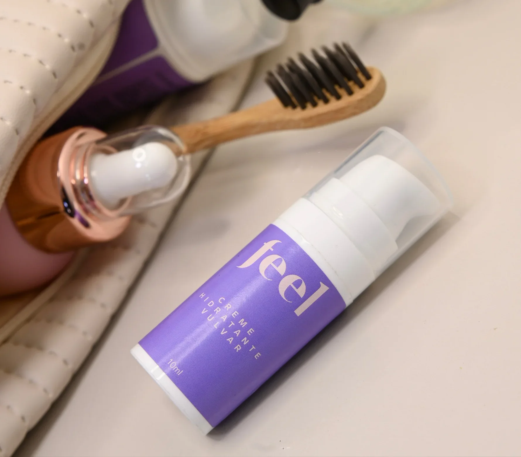 Creme hidratante vulvar roxo ao lado de uma escova de cerdas escuras. Ideal para autocuidado íntimo.