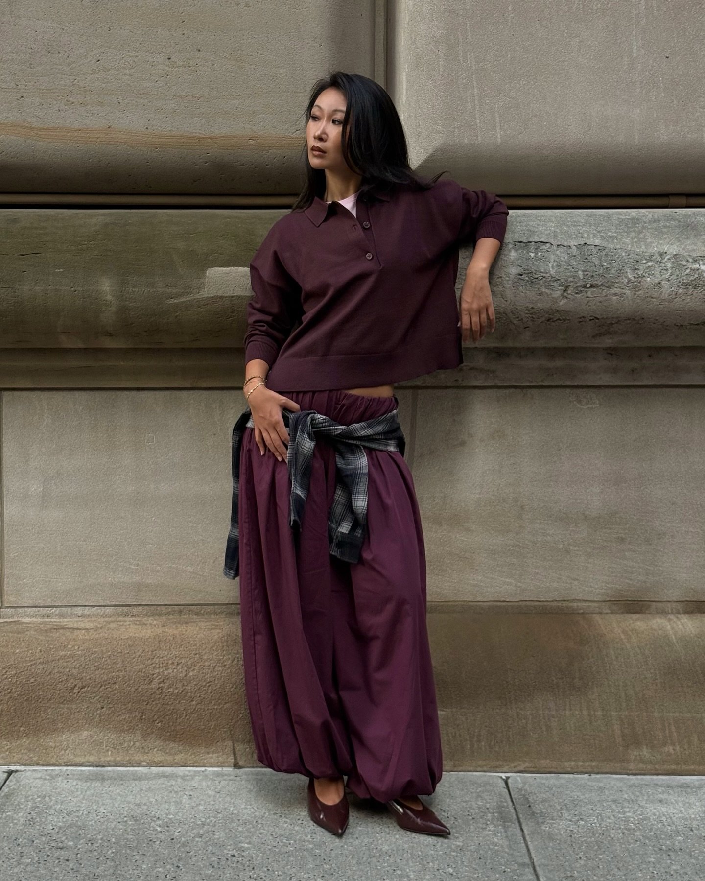 Pessoa usando roupa elegante em tons de vinho, com blusa de mangas compridas e saia ampla. Camisa amarrada na cintura. Looks bonitos.