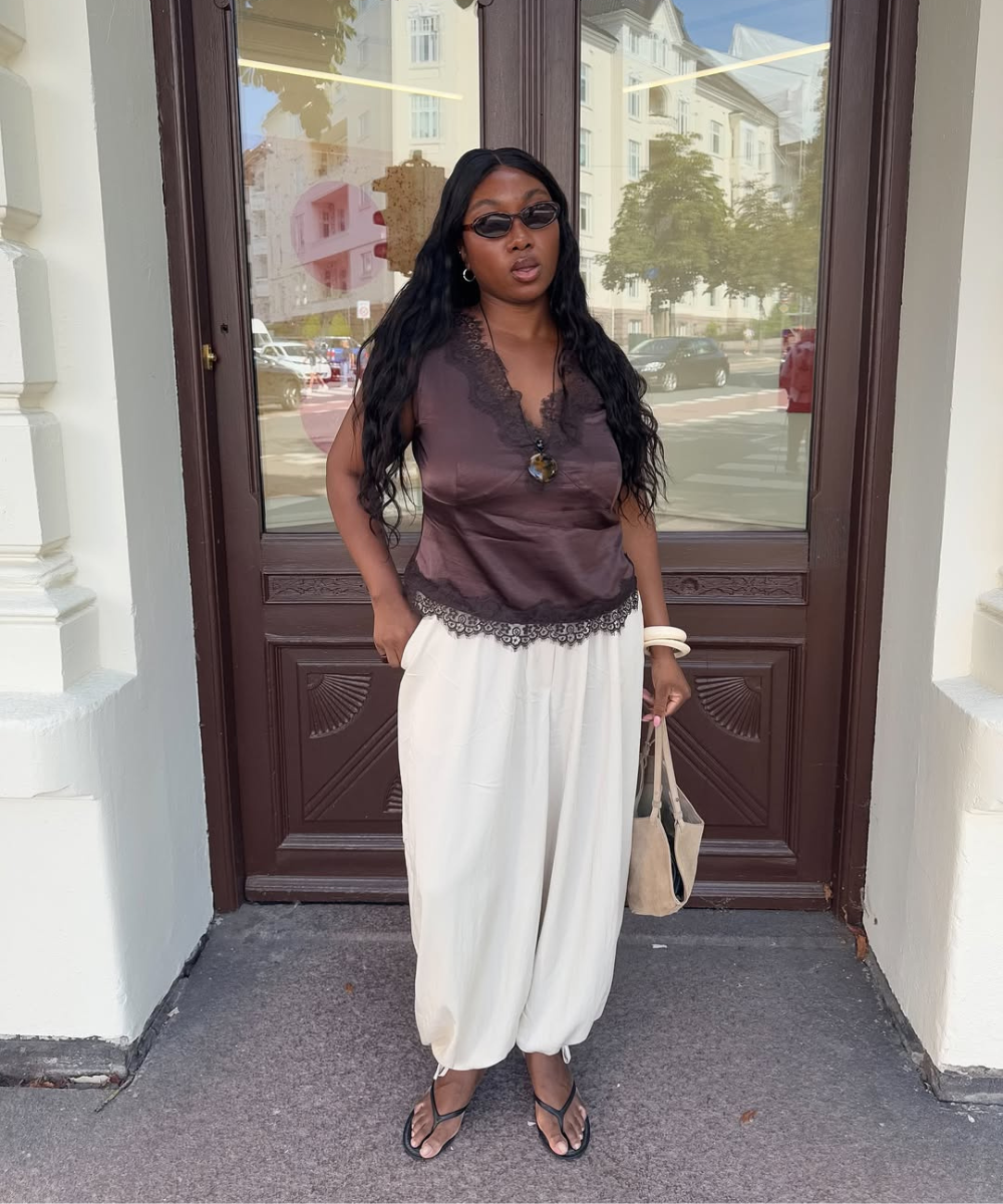 Mulher com blusa marrom e calça larga bege, criando um visual confortável e estiloso.