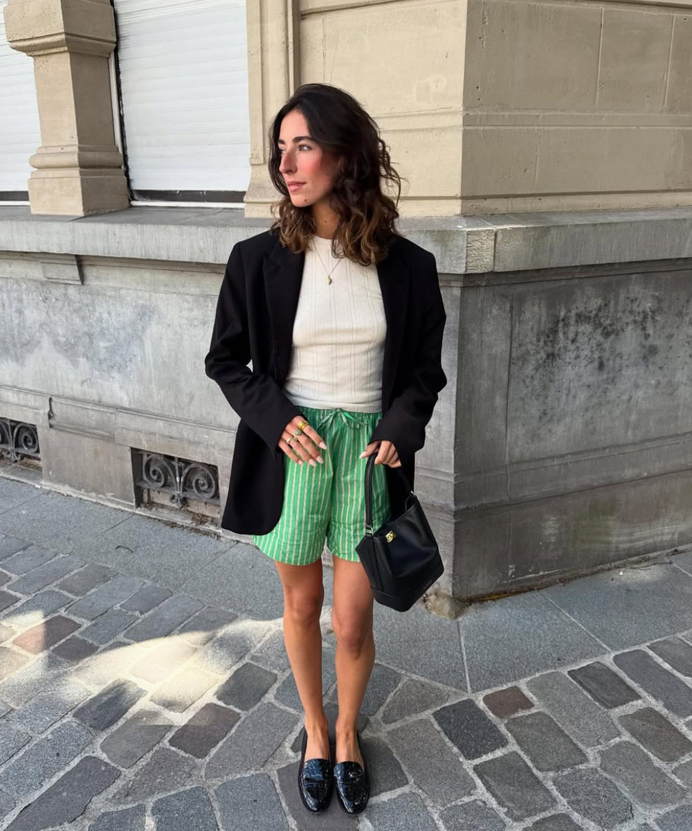Meia-estação urbana: blazer preto, blusa clara, shorts listrados verdes e sapatos pretos. Looks tendência para primavera.