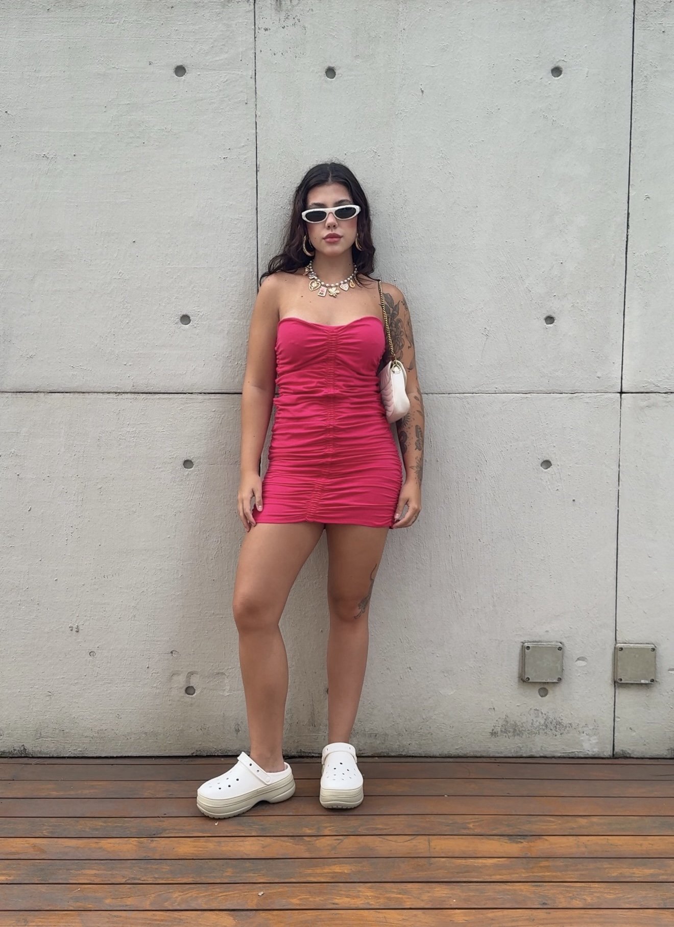 Vestido rosa vibrante e Crocs brancos em composição elegante com acessórios chiques. Looks estilosos com Crocs.