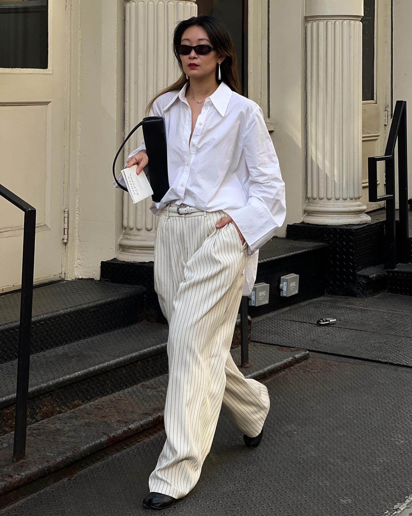 Pessoa caminhando com camisa branca e calça listrada, ideal para melhores looks de trabalho.