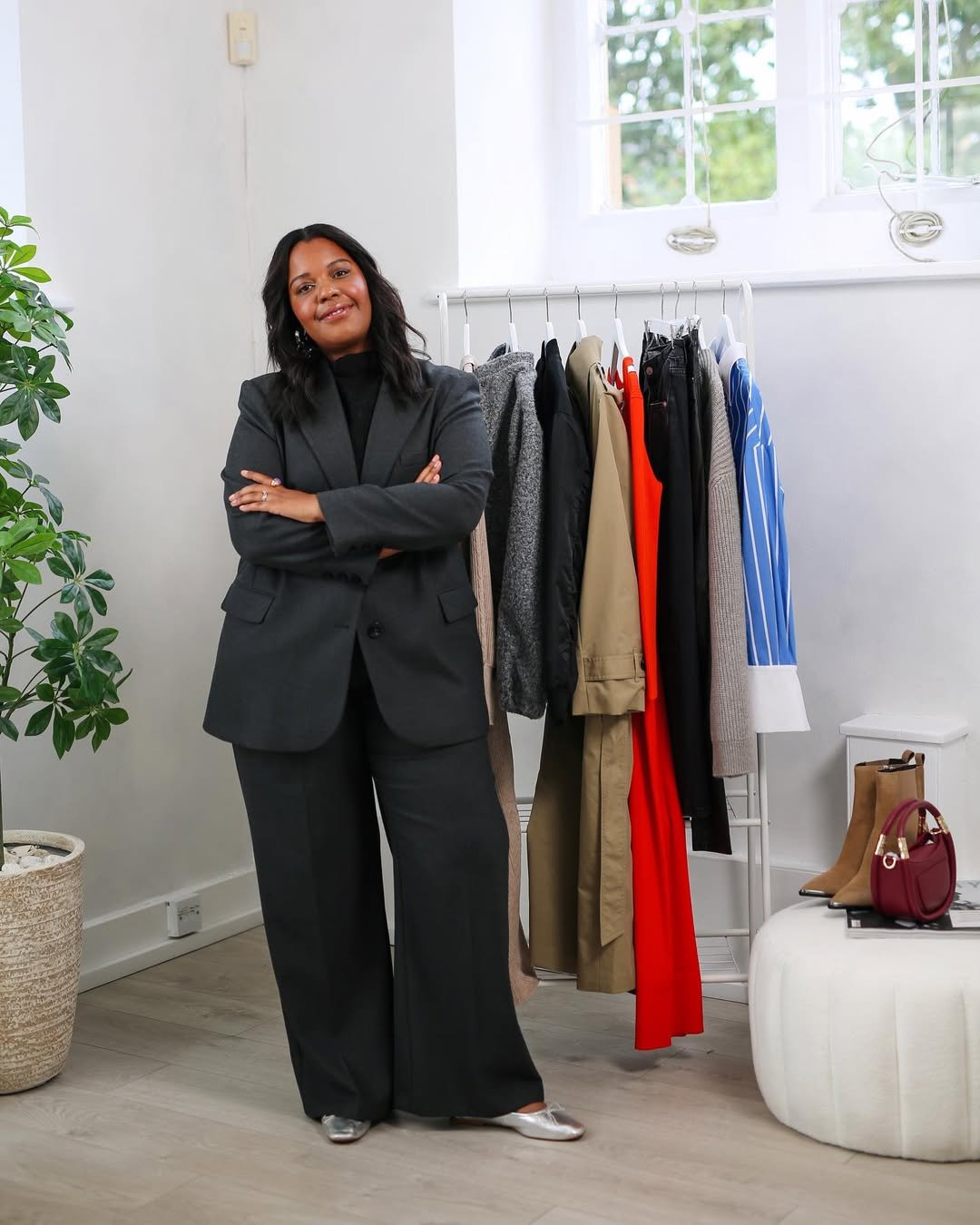 Pessoa com terno preto em frente a arara de roupas variadas, exemplificando melhores looks de trabalho.