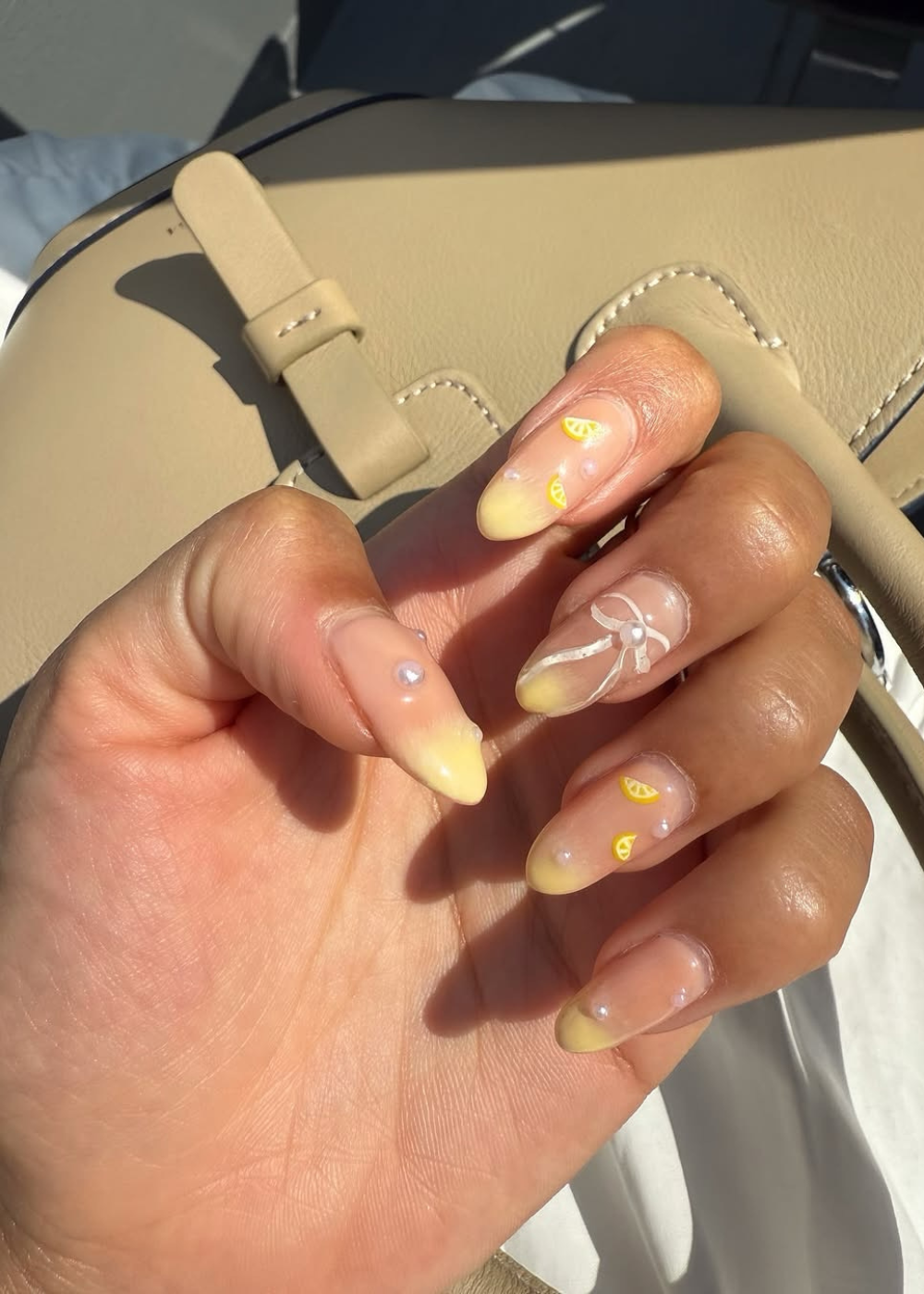 Unhas decoradas com limões e pérolas em tons pastel, destacando nail arts tendência do verão 2026.