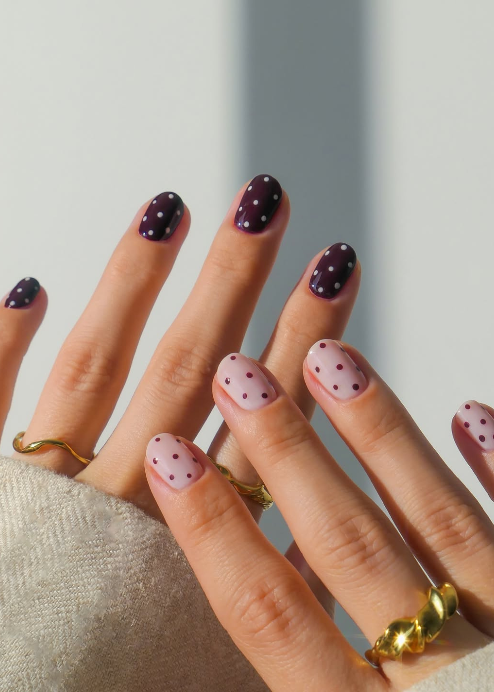 Unhas decoradas com poás brancos sobre fundo roxo e poás roxos sobre fundo rosa, tendência do verão 2026.