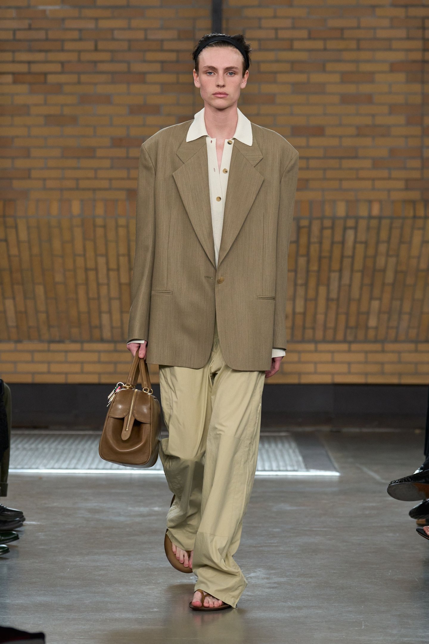 Modelo com terno bege e bolsa marrom na passarela da New York Fashion Week SS26.