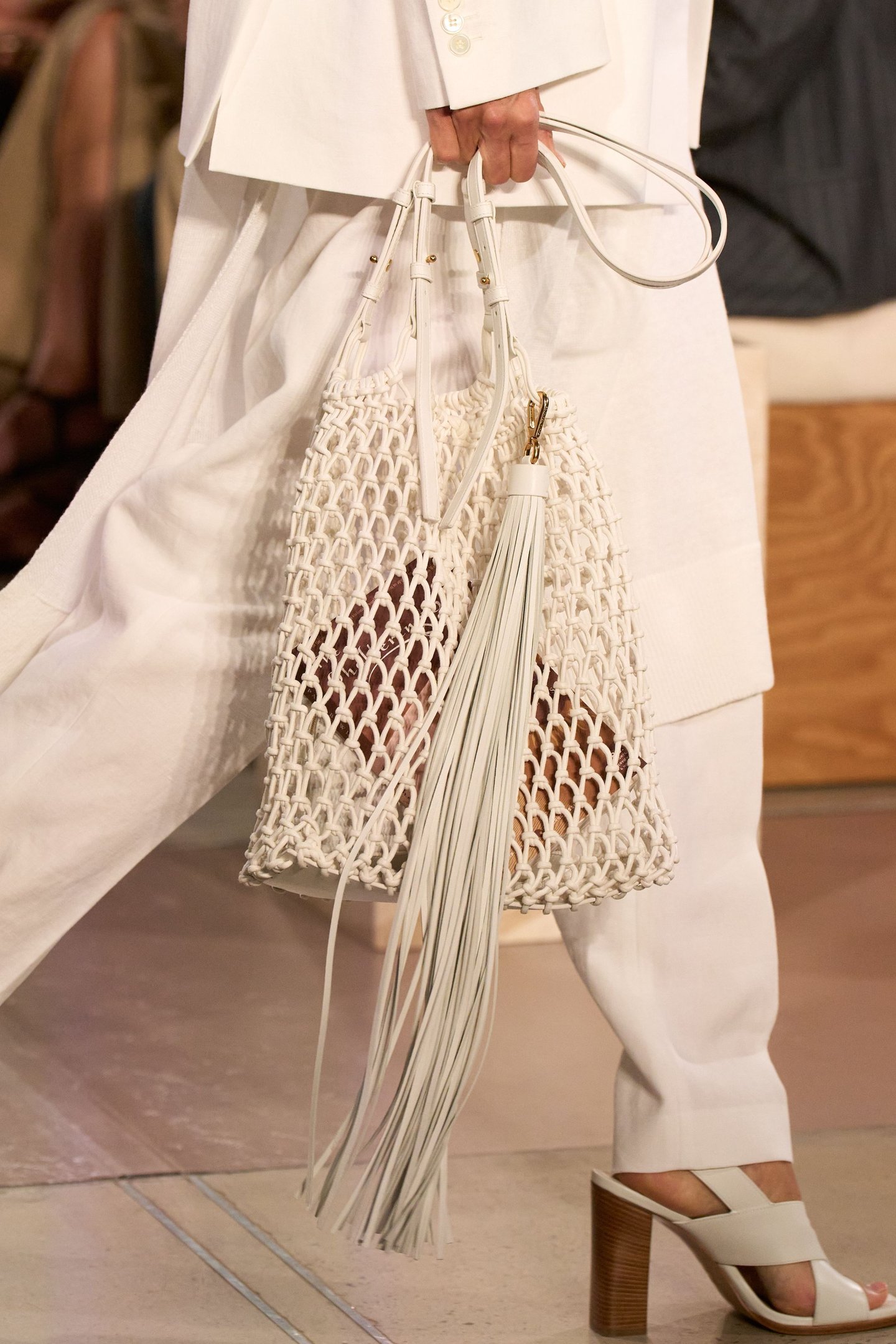 Bolsa de crochê branca com franjas longas, combinada com traje claro, na New York Fashion Week SS26.