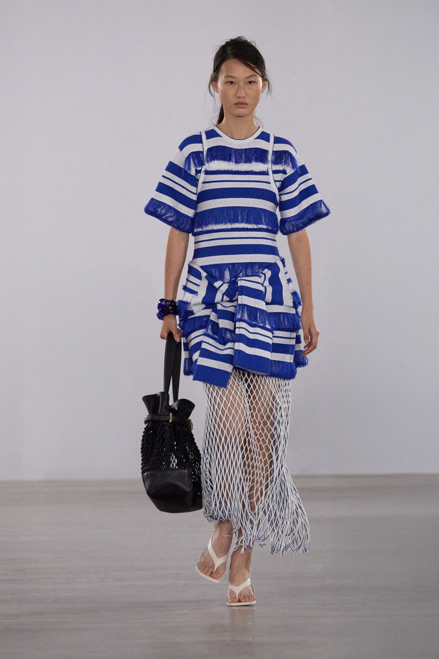 Modelo com vestido listrado azul e branco e saia de rede na New York Fashion Week SS26.