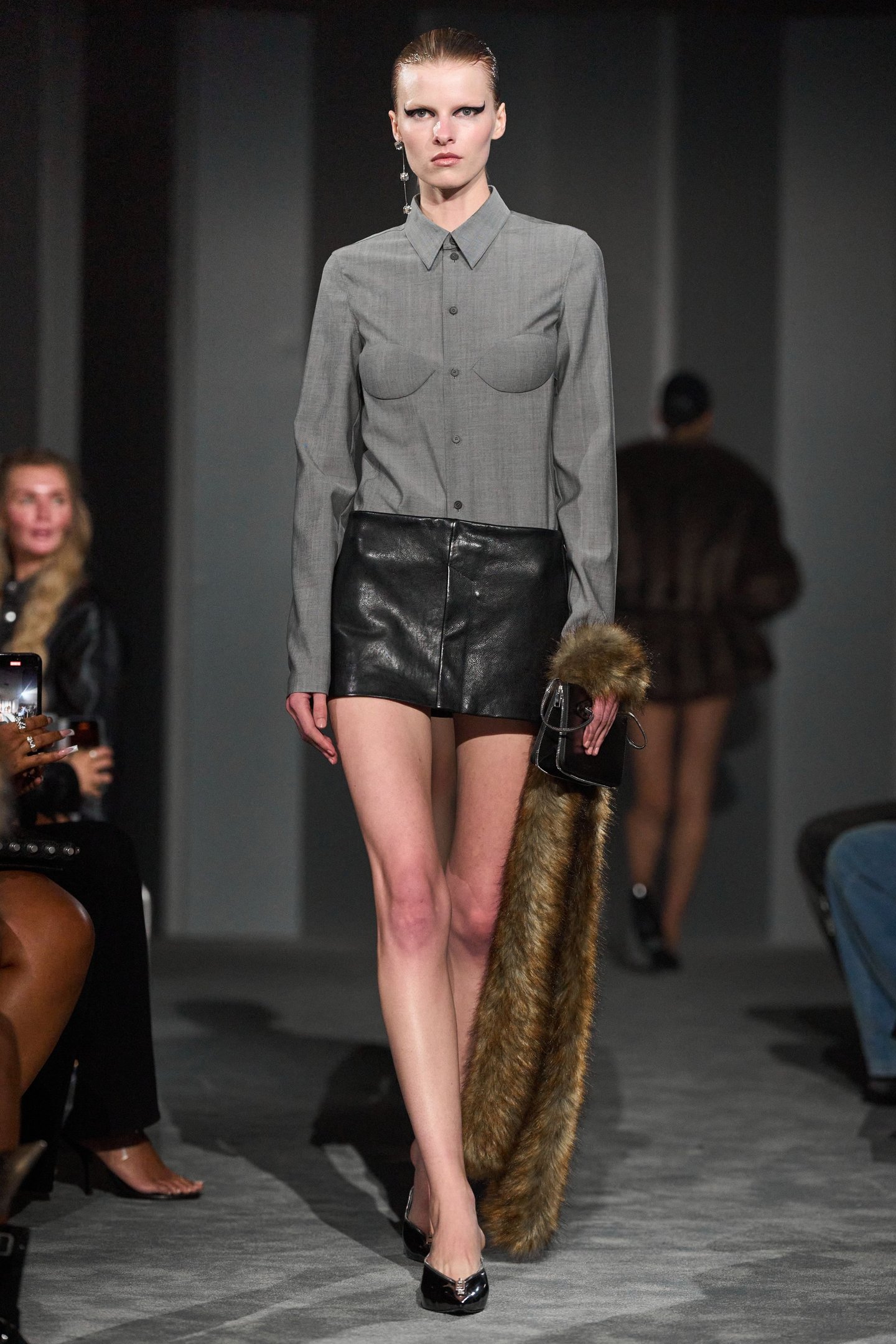 Modelo desfila com camisa cinza e saia de couro na New York Fashion Week SS26.