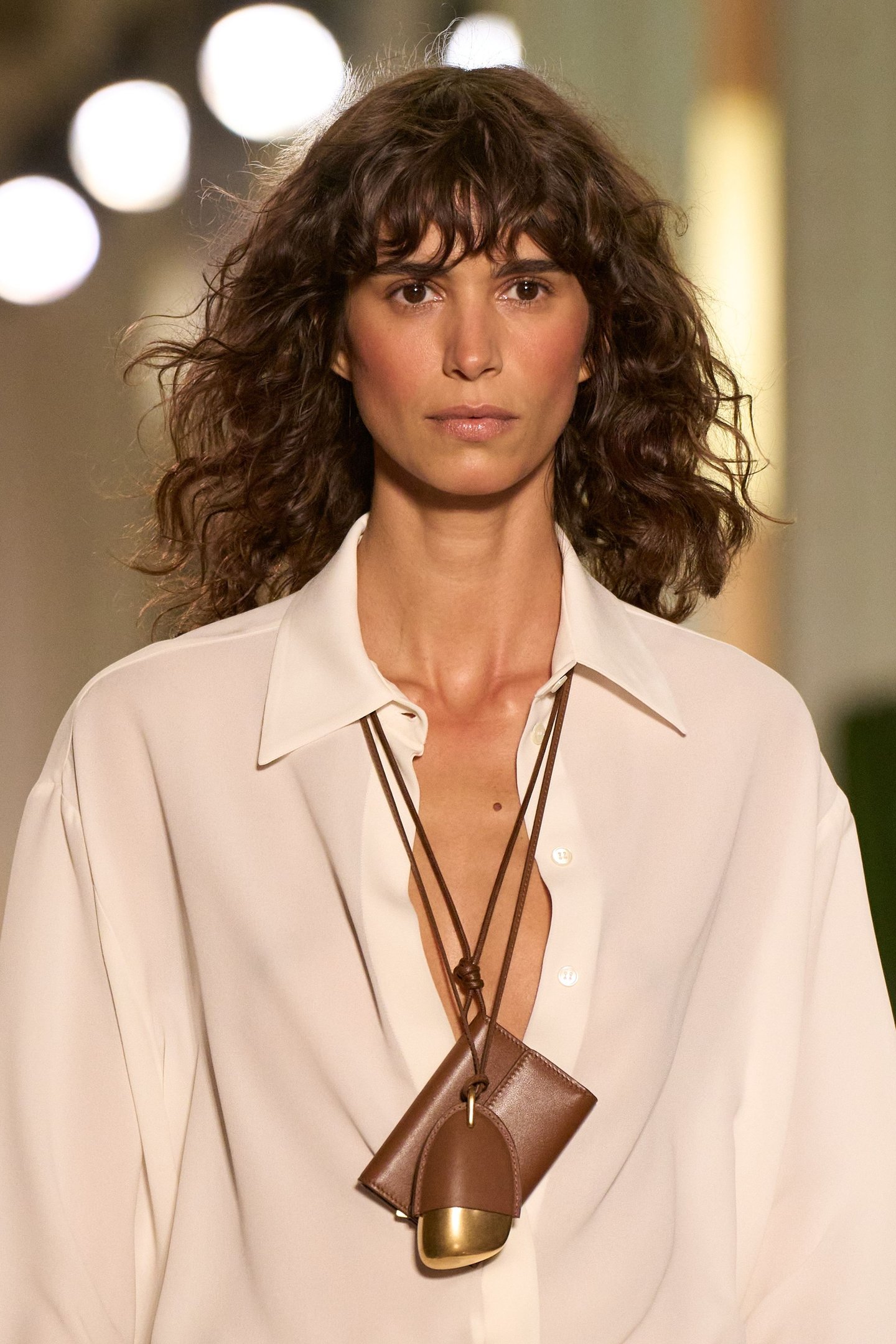 Modelo com camisa branca e colar de couro, desfilando na New York Fashion Week SS26.