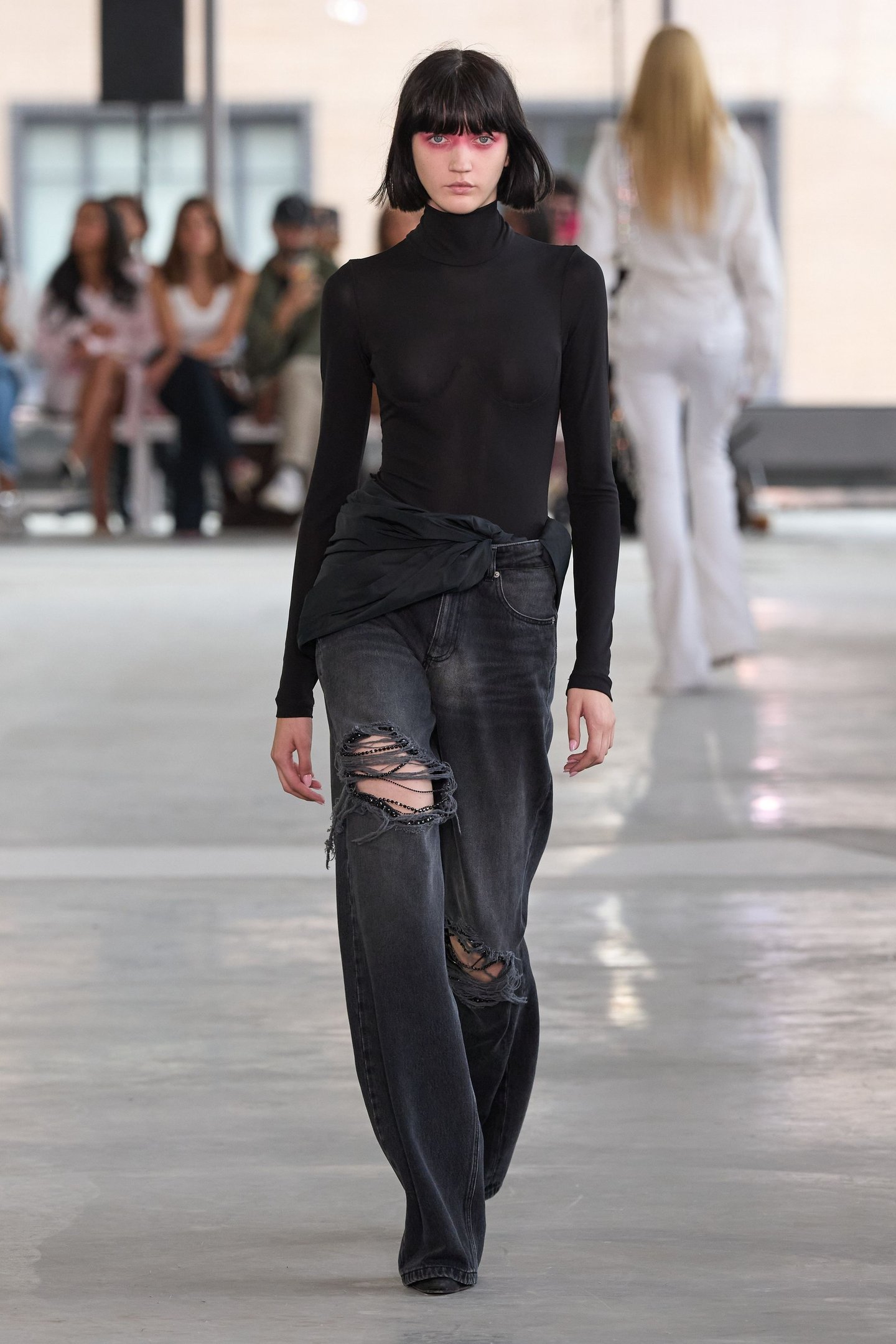 Modelo com suéter preto transparente e calça jeans rasgada na New York Fashion Week SS26.