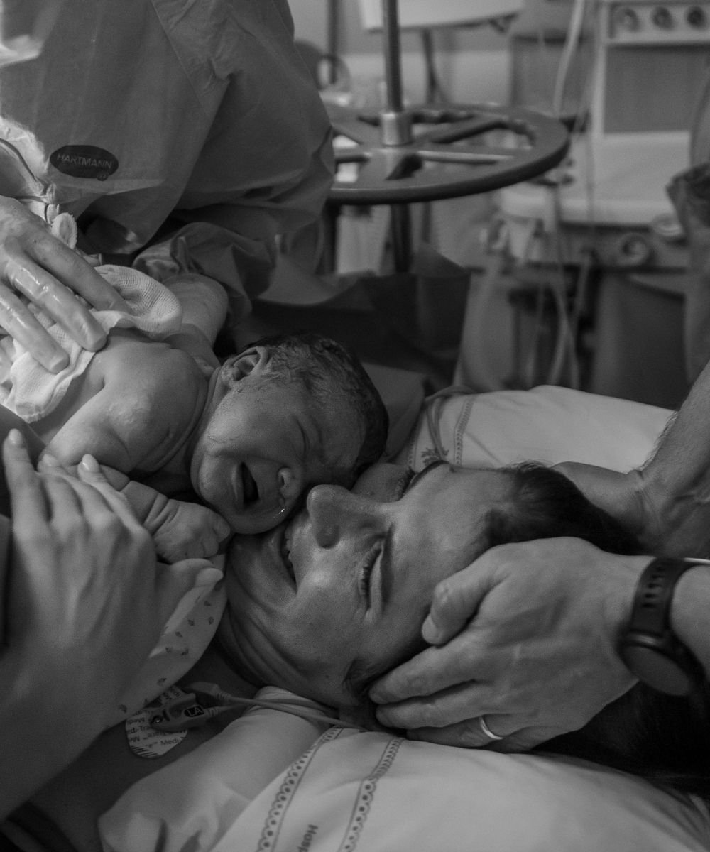 Mãe sorridente segura recém-nascido nos braços, expressando emoção e conexão após o parto. Mostrando a importância da fertilidade feminina.