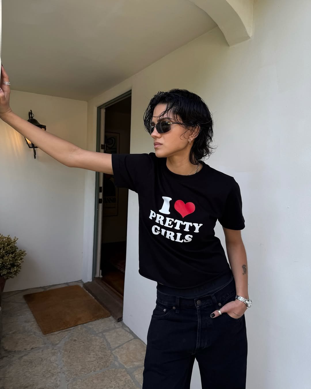 Pessoa usando óculos escuros e graphic tee preta com a mensagem