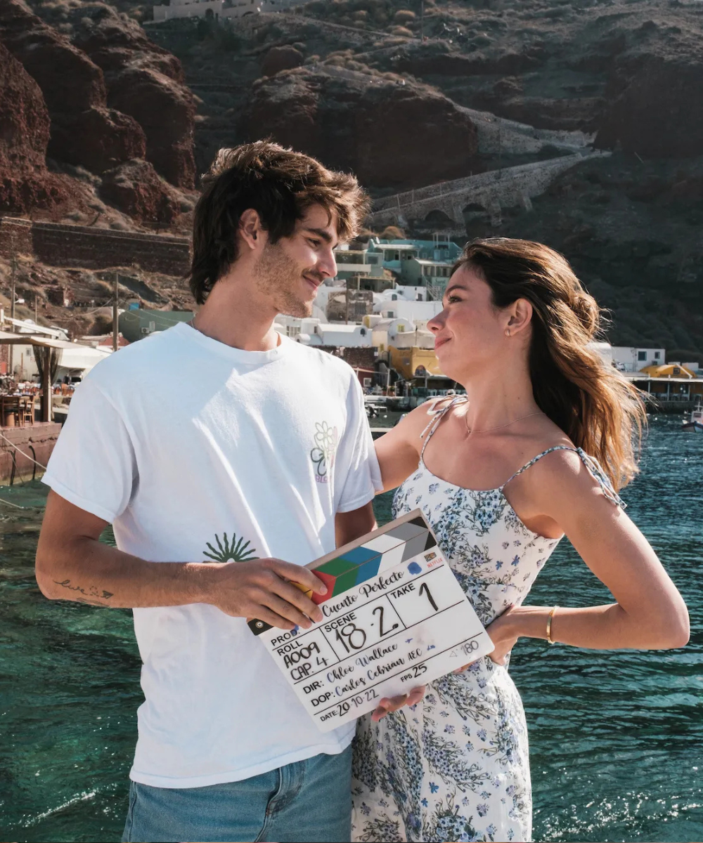 Um casal sorri, segurando uma claquete de filme