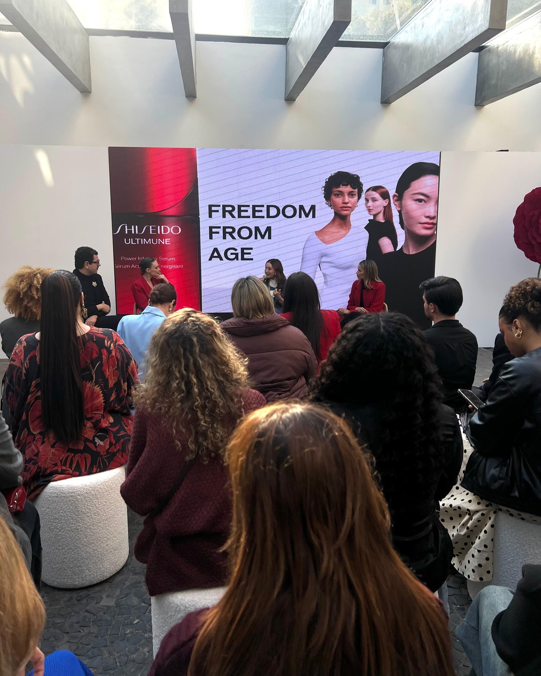 Pessoas assistem a apresentação da Shiseido com painel exibindo 
