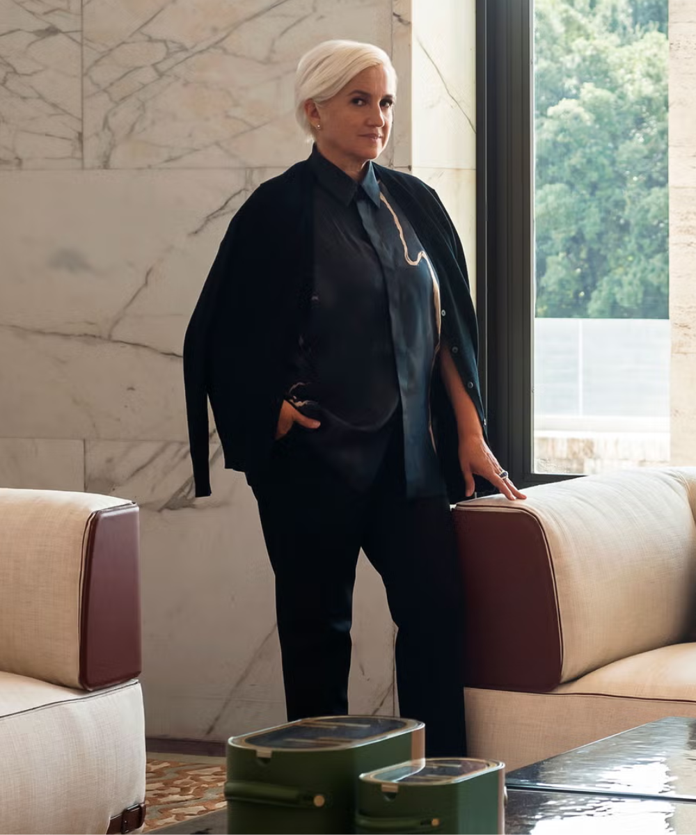 Silvia Venturini cabelo curto e loiro, vestida de preto, em frente a uma janela.