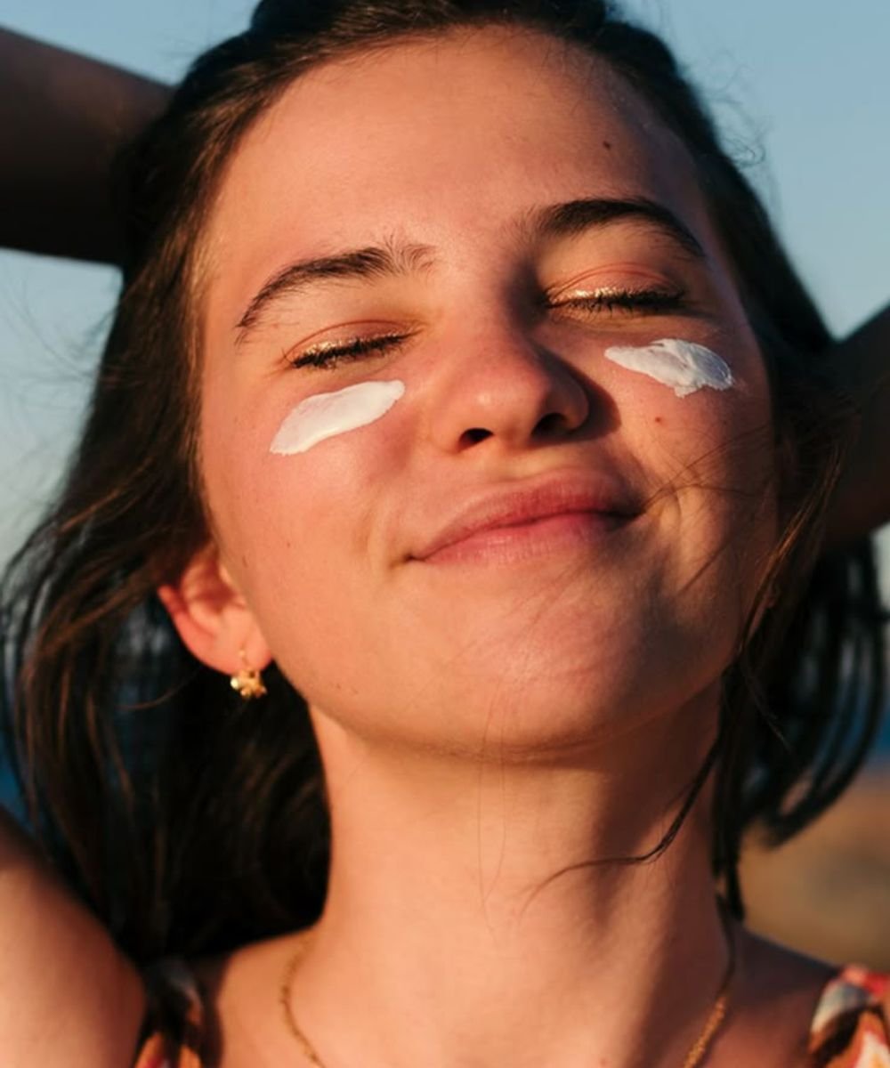 Rosto sorridente com creme nas bochechas, representando um ritual de skincare básico.