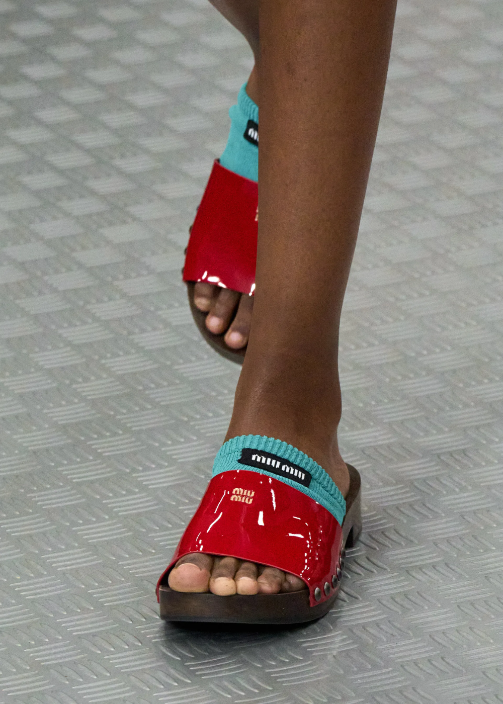 Sandália vermelha e meia turquesa em passarela de moda.
