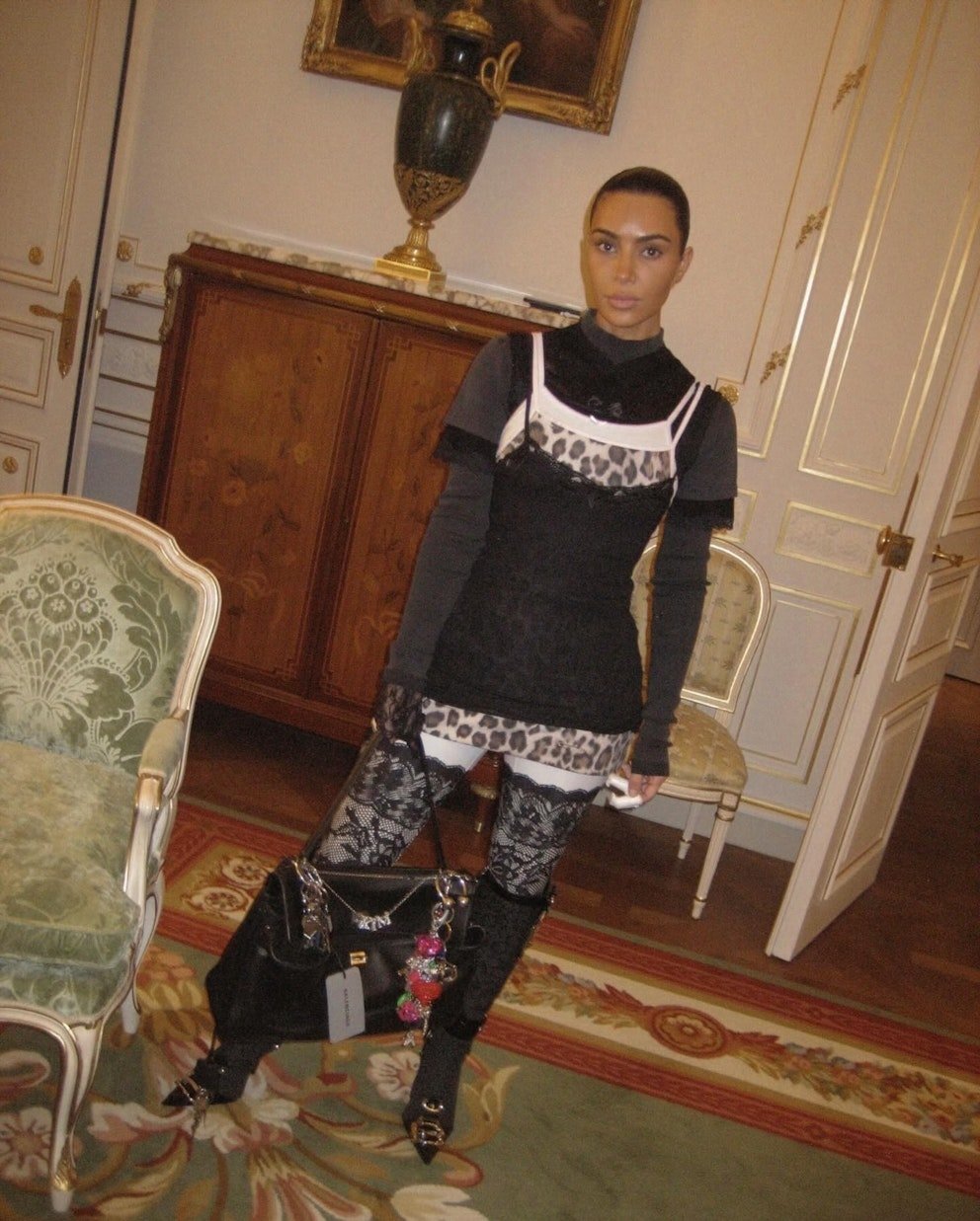 Pessoa vestindo roupa sobreposta com estampas de oncinha e renda, segurando bolsa grande, tendência dos anos 2000.