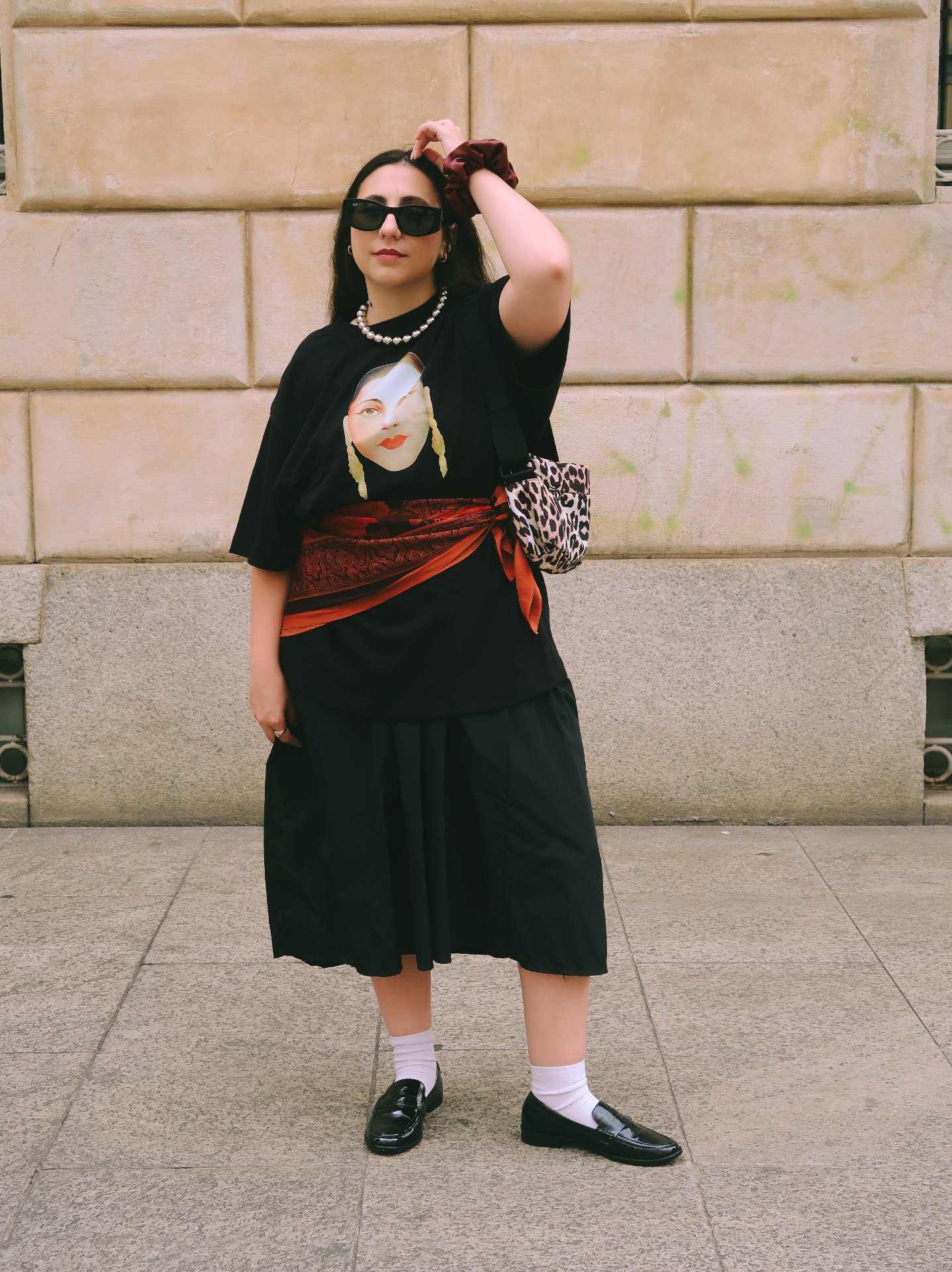 Mulher com look moderno em roupas pretas, óculos escuros e sapatos tipo flat, em sintonia com tendências de flat.