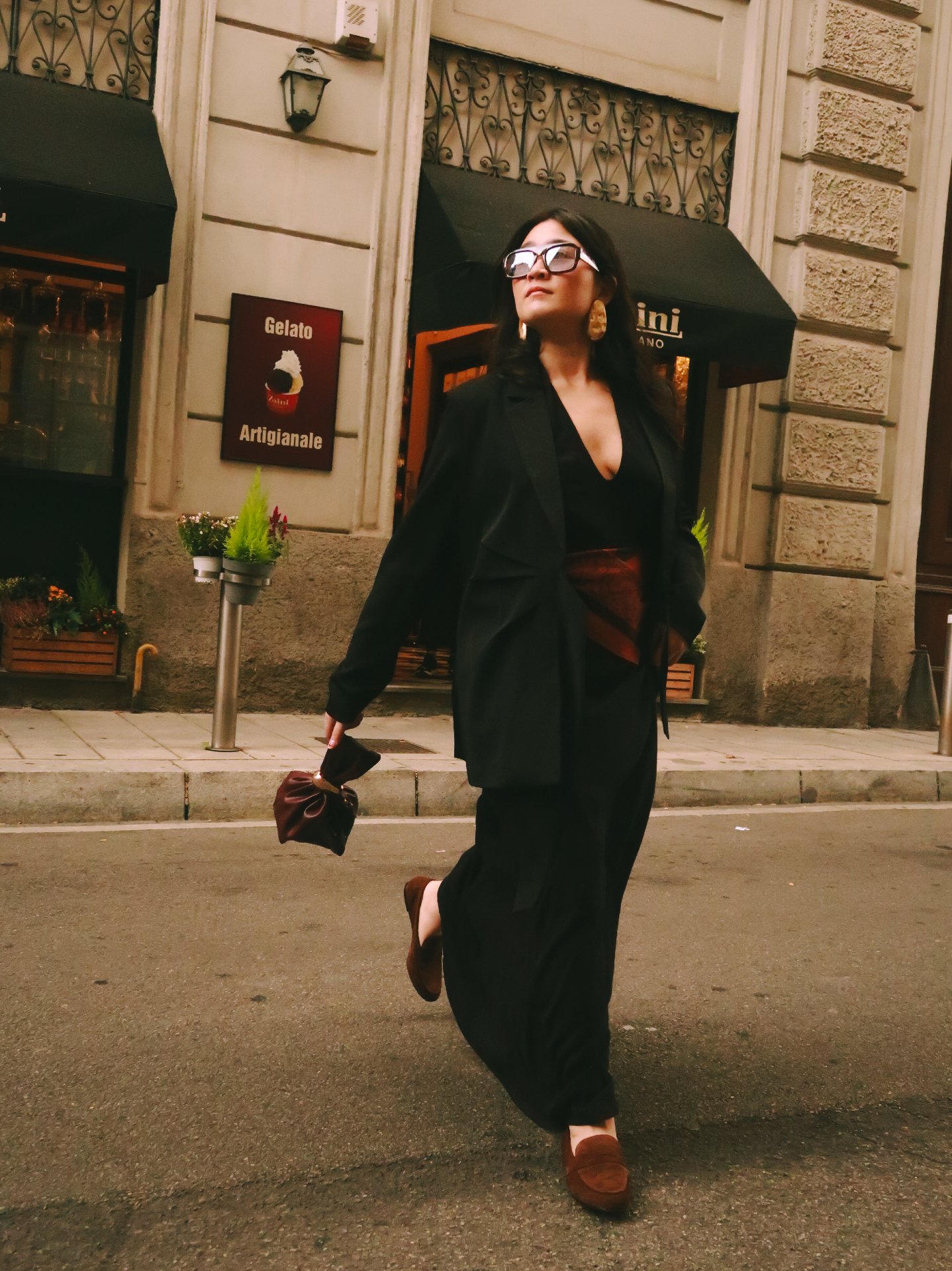 Pessoa caminhando pela rua com traje elegante preto e sapatos baixos, destacando tendências de flats.