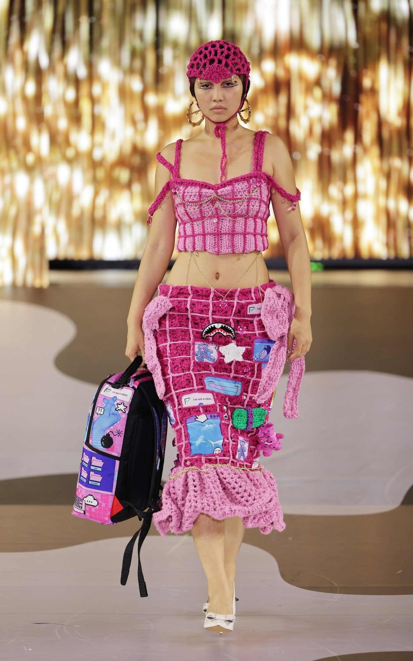 Modelo usando conjunto de crochê rosa com textura e adornos criativos, desfilando na London Fashion Week SS26.