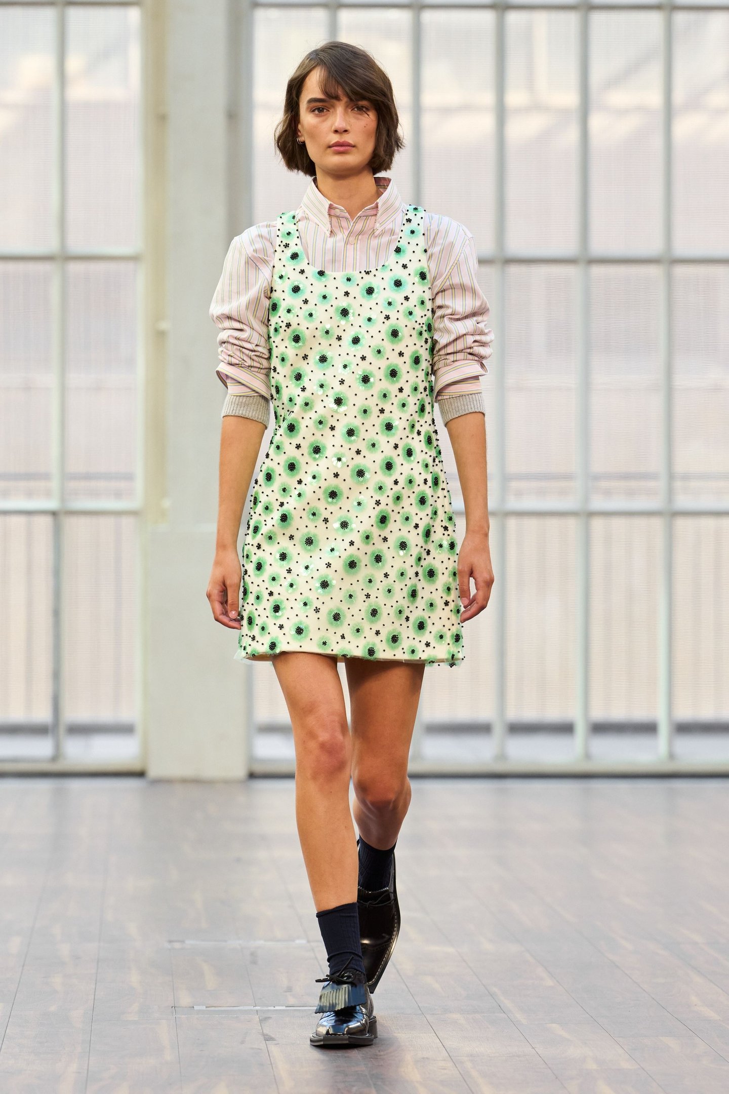 Modelo com vestido estampado floral verde e camisa listrada na London Fashion Week SS26.
