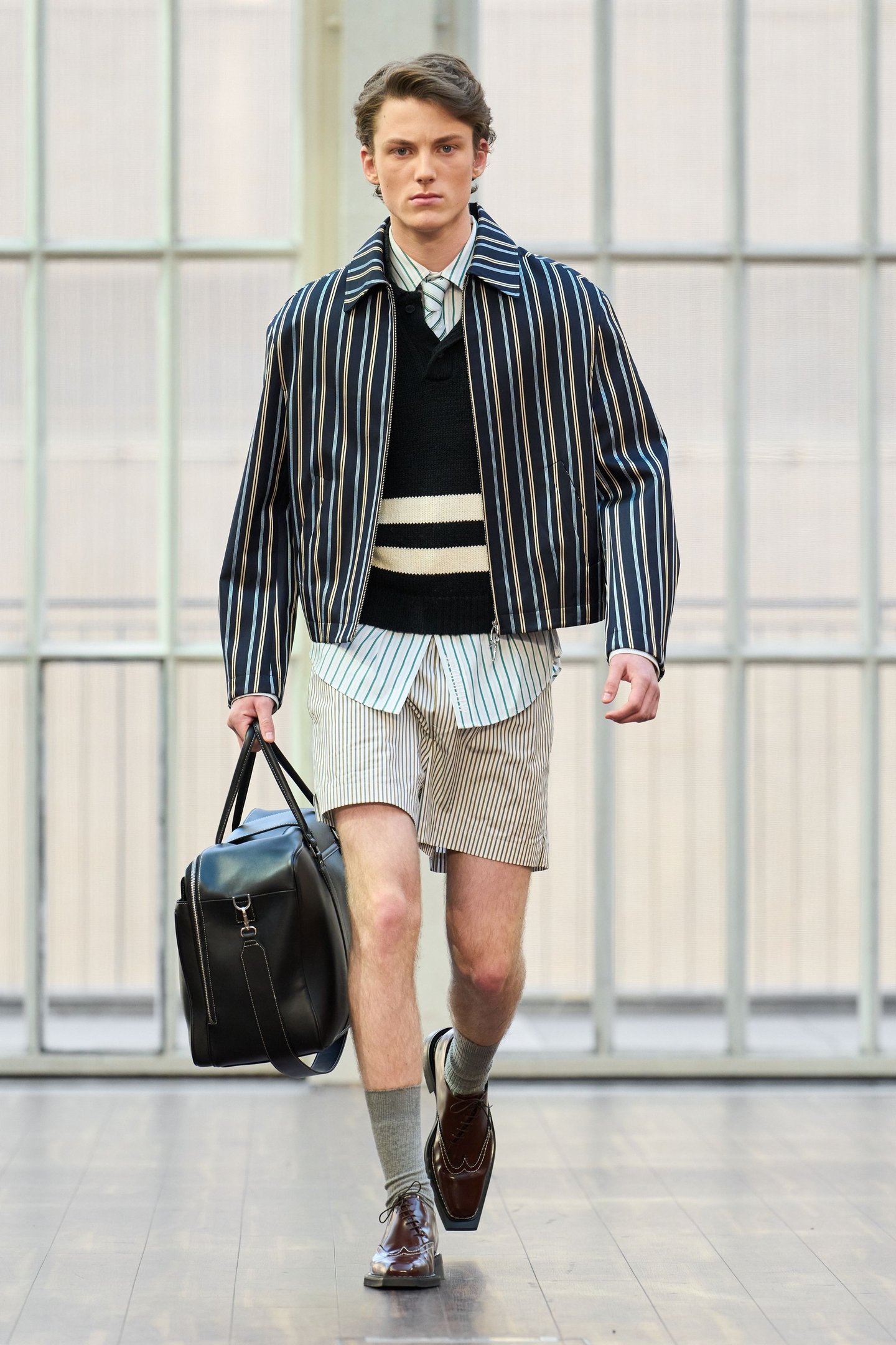 Modelo usando look listrado com bolsa preta na London Fashion Week SS26.